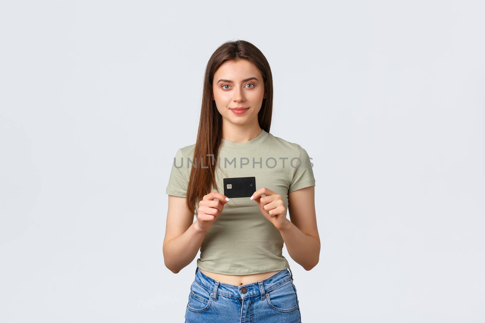 Shopping mall, lifestyle and fashion concept. Attractive caucasian female customer showing credit card, prefet paying contactless or using deposit cash, standing white background.