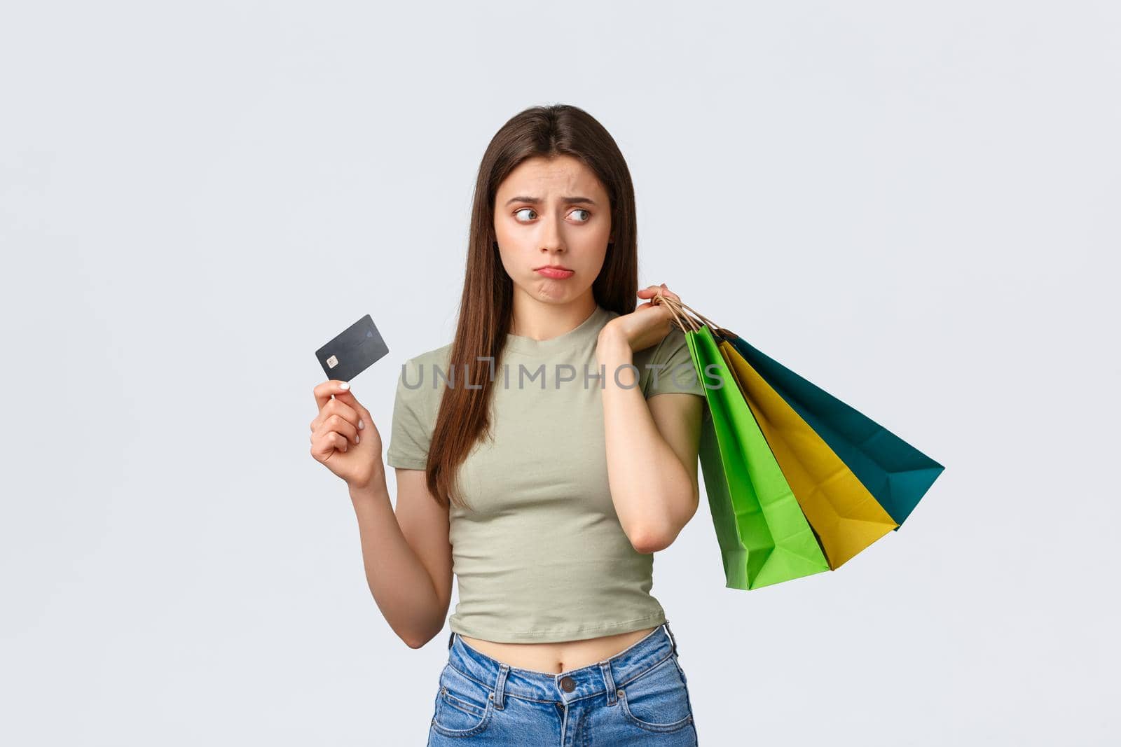 Shopping mall, lifestyle and fashion concept. Gloomy and sad cute pouting woman complaining on empty credit card, looking right disappointed as holding bags over shoulder by Benzoix