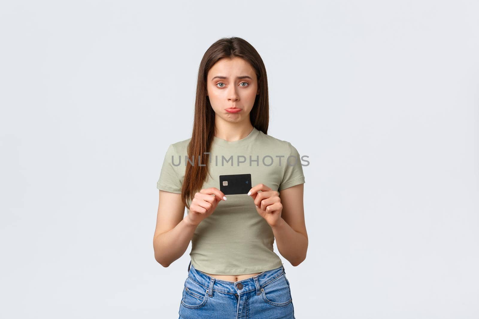 Shopping mall, lifestyle and fashion concept. Gloomy and disappointed pouting cute woman in casual outfit showing credit card without no money, wasted all cash on new clothes.