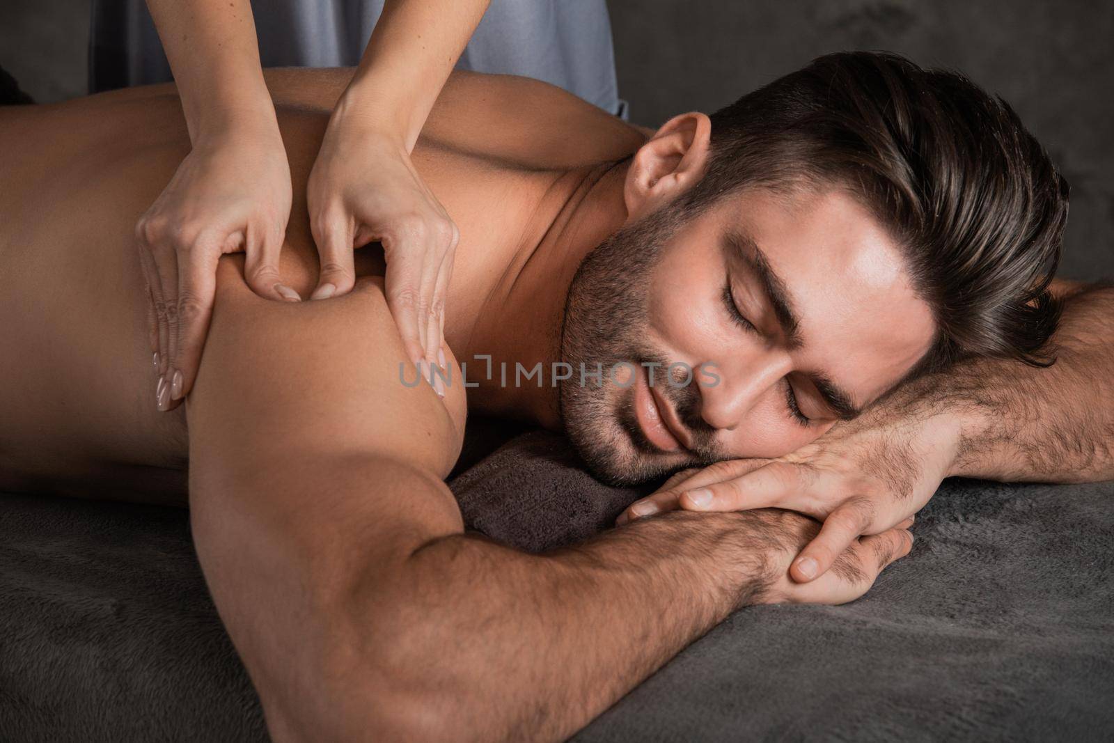 A good-looking man getting a back massage lying down