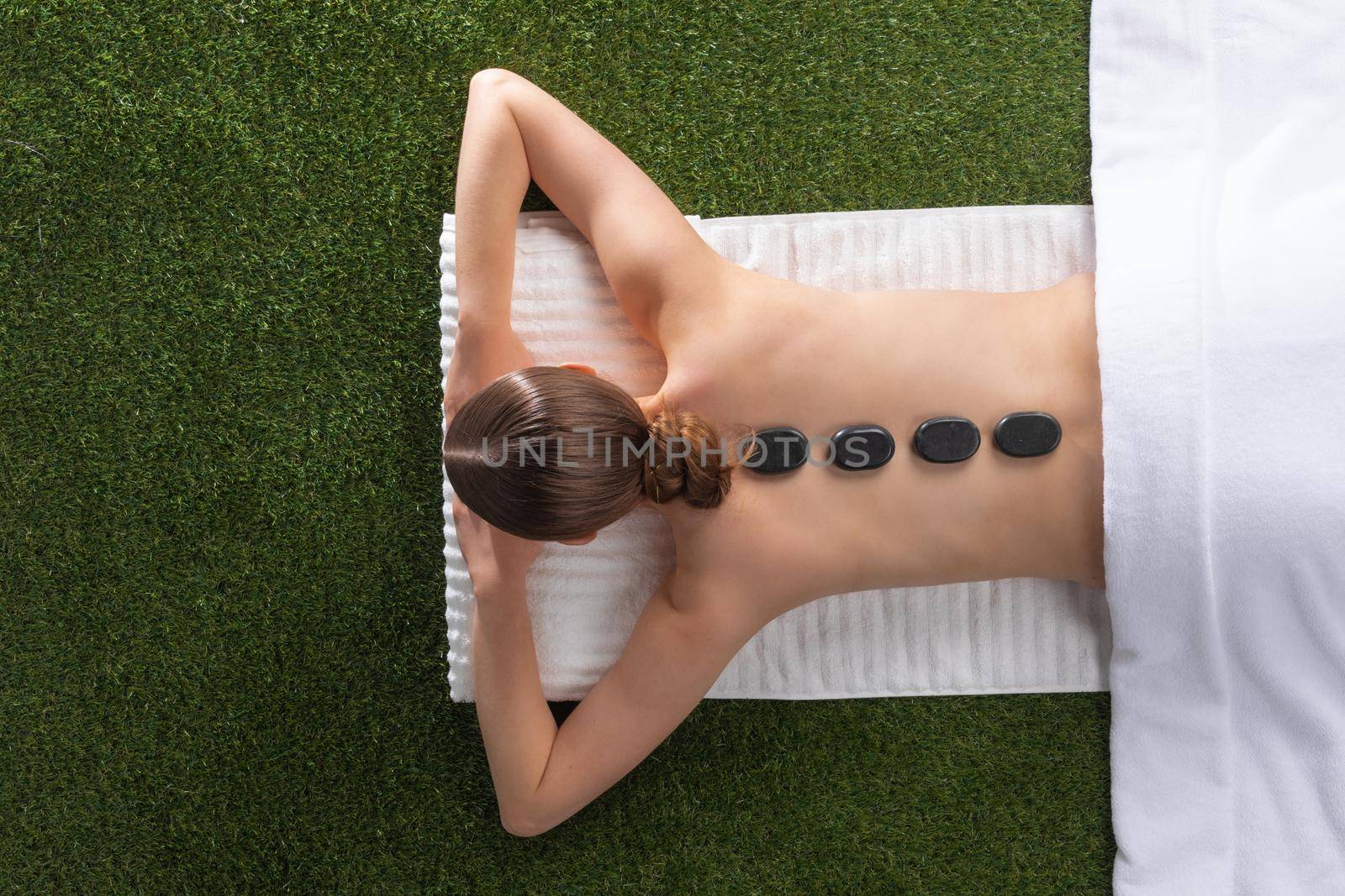 Top view of back of pretty woman lying on spa bed and have hot stone, body and skin treatment in relaxation time, spa concept