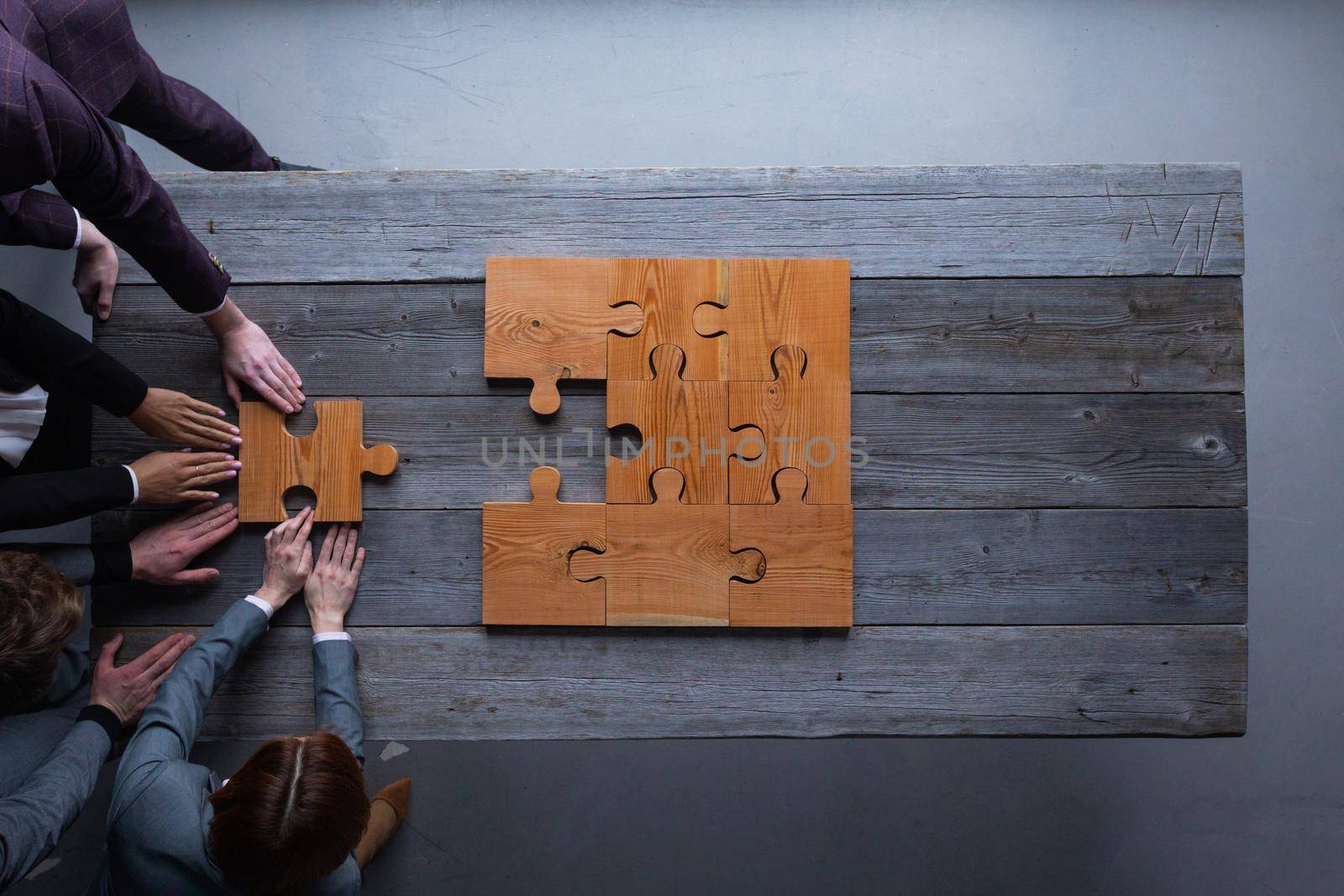 Finally finding solution, business team putting last piece of puzzle at office meeting