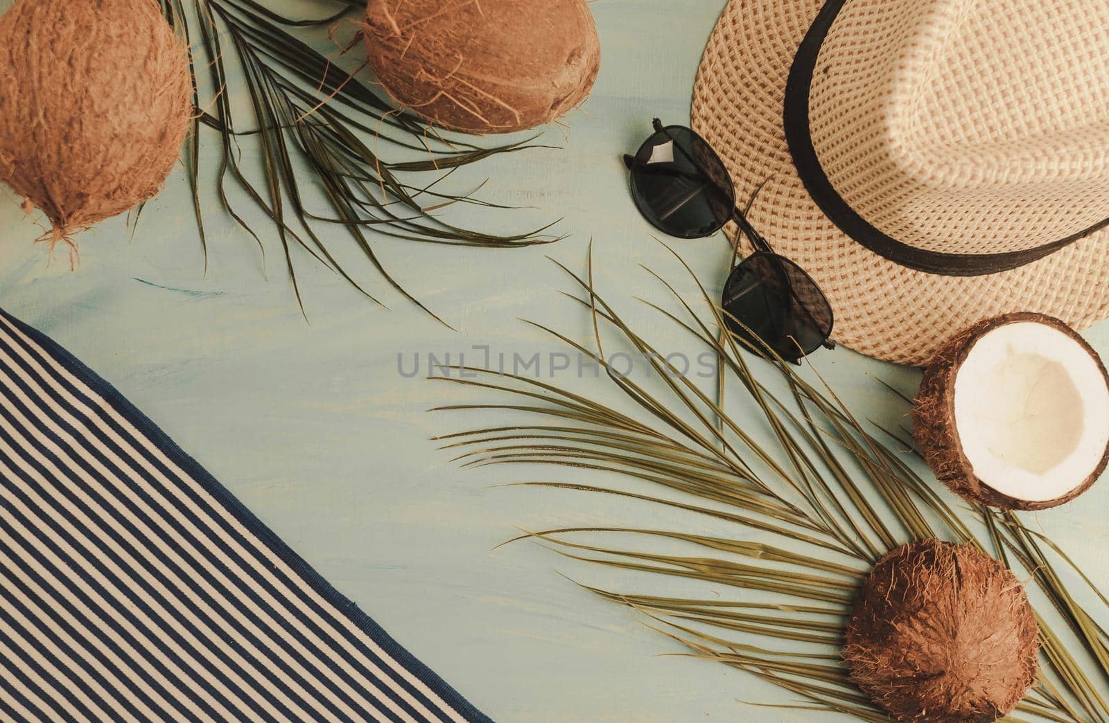 Summer composition or layout. Tropical palm leaves, hat, glasses, beach towel, coconut on a background of sea greens. The concept of the summer season and heat. Flat lay, top view, copy space