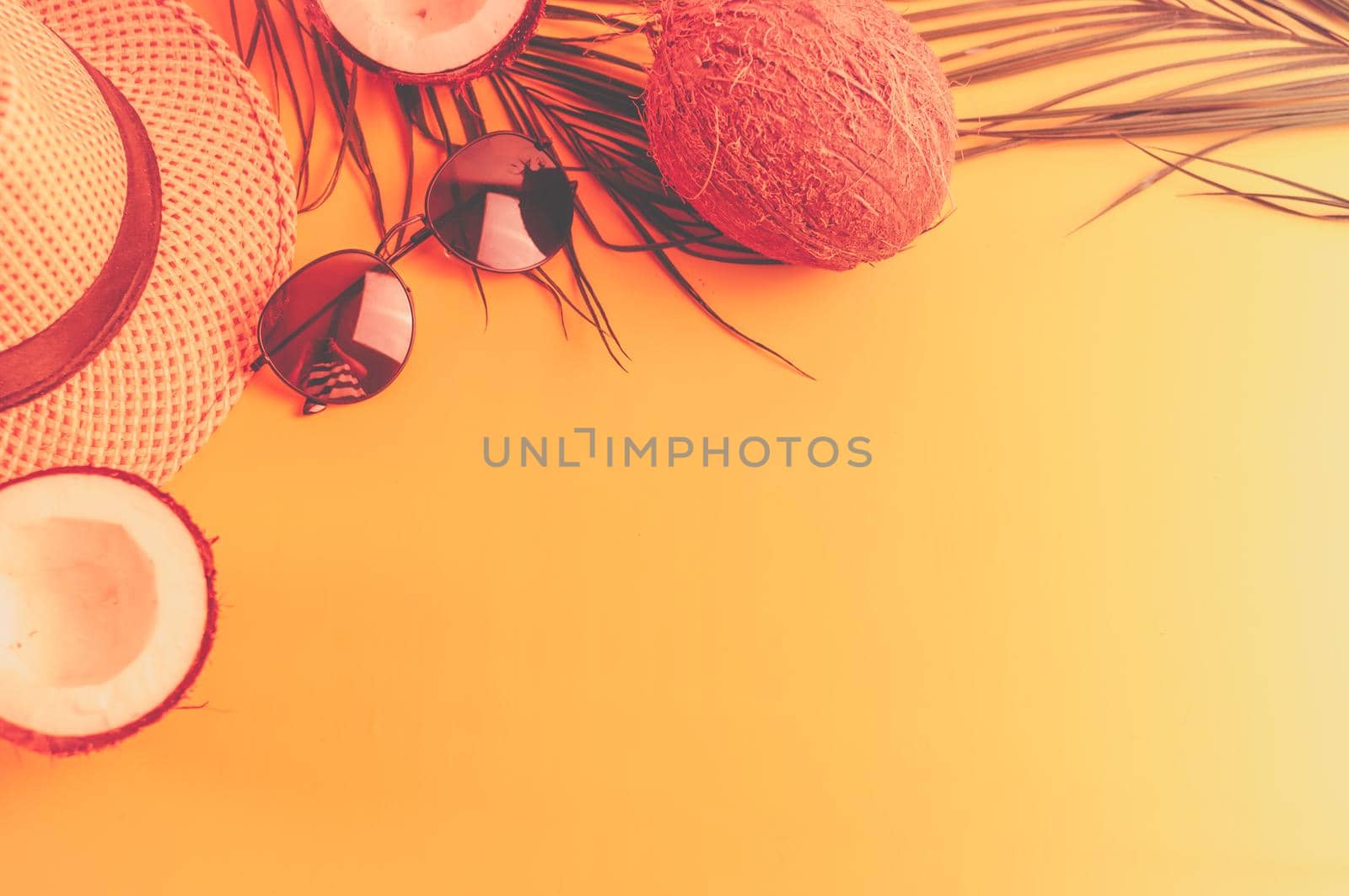 Summer composition with neon lights. Tropical palm leaves, hat, glasses and broken coconut on a sandy background. The concept of the summer season, parties and heat. Flat lay, top view, copy space