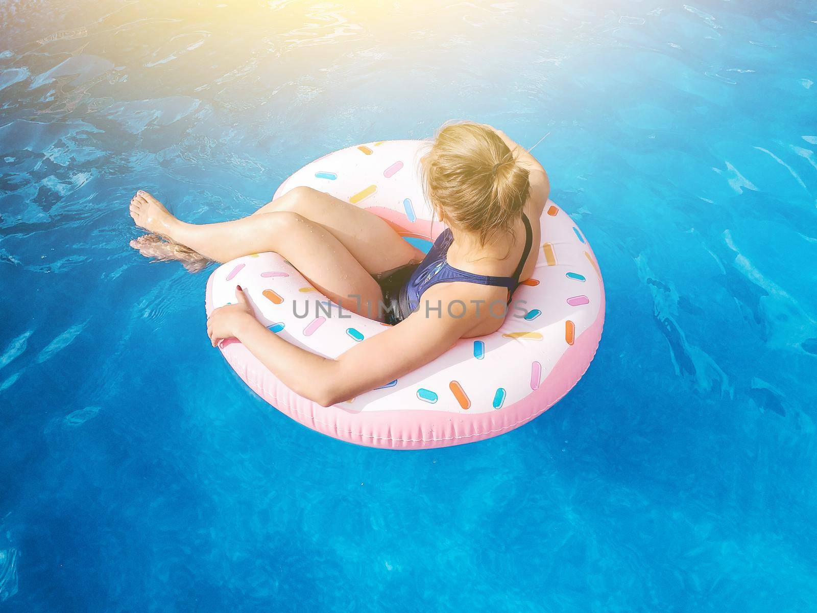 Summer warm vacation. The girl sits on a rubber ring in the form of a donut in a blue pool. Time to relax on an air mattress. Having fun in the water for a family vacation. Sea resort.