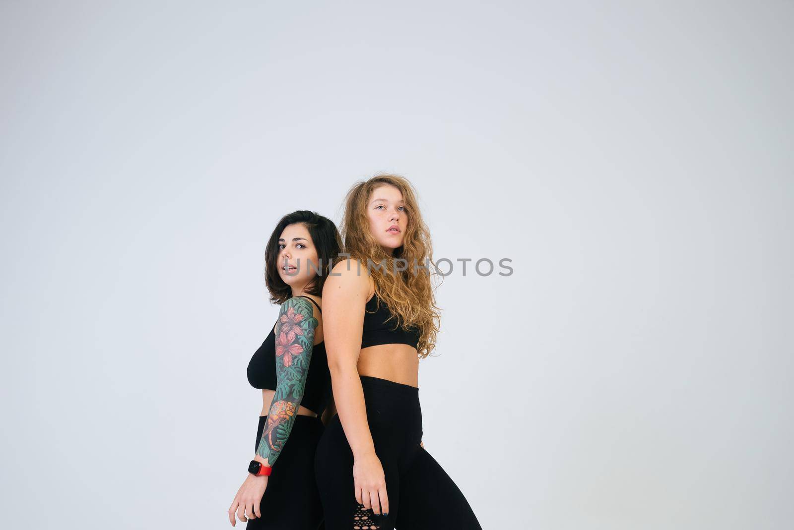 Two young women posing over white background. Two girlfriends, body positive concept