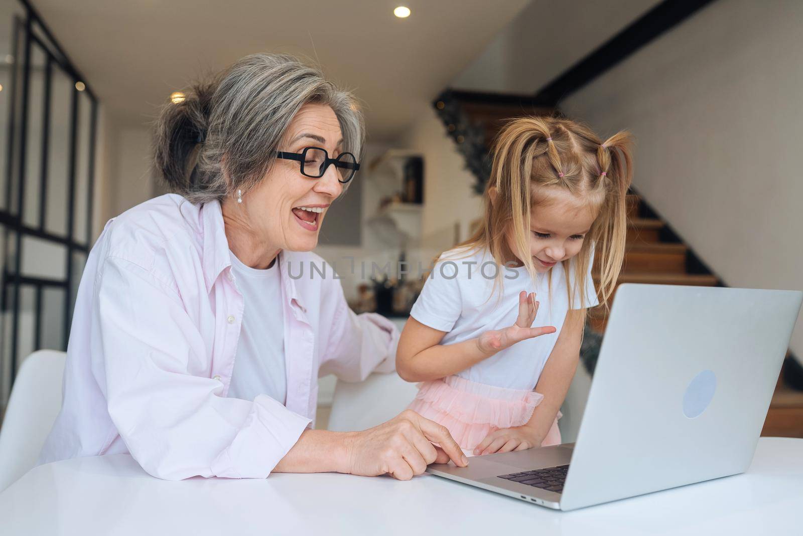 Child and granny looking at the camera with laptop at home