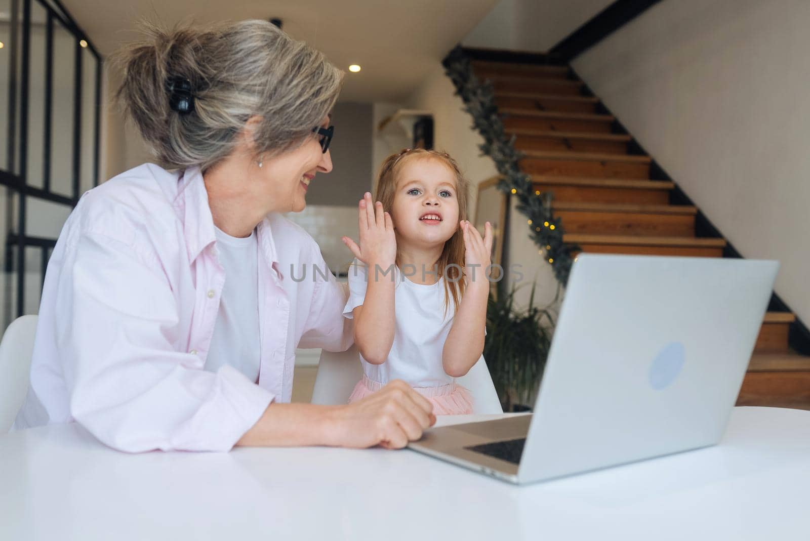 Child and granny looking at the camera with laptop at home