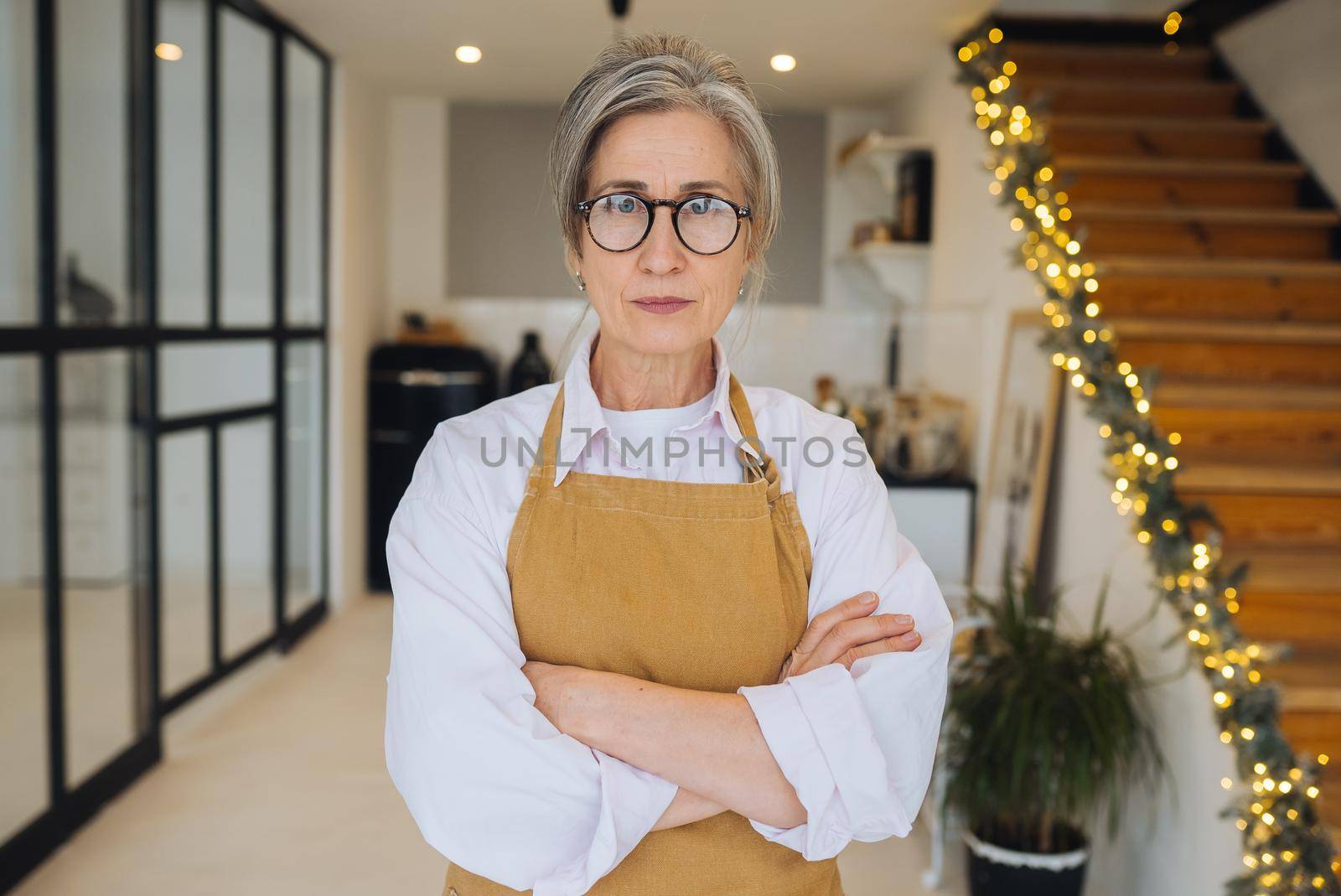 Portrait of strict granny standing in displeased pose keeping arms folded on her chest