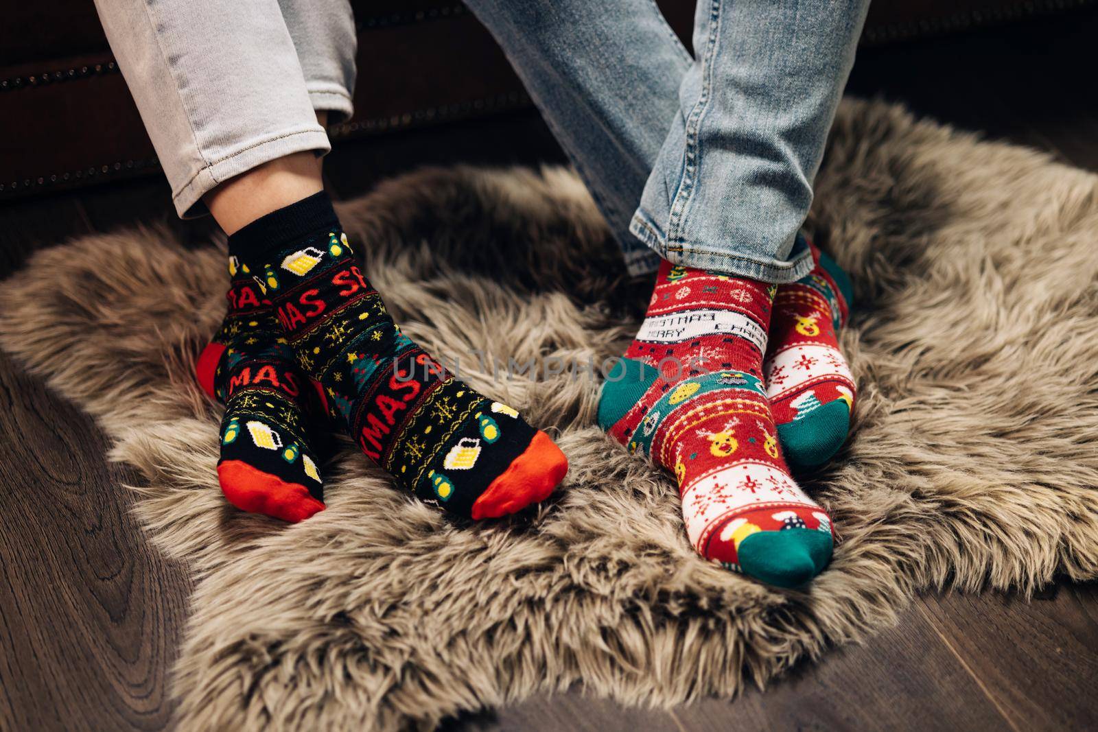 Feet in colorful wool socks. Legs in winter christmas socks in cozy home interior. Christmas socks. Two pairs of foot, dressed in Xmas soks. Atmosphere of Christmas. The idea for happy family