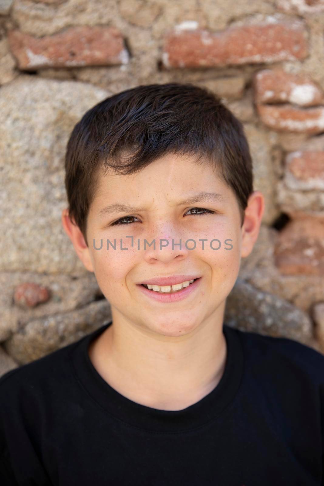 Portrait of handsome male child in the city outdoors. Natural light.