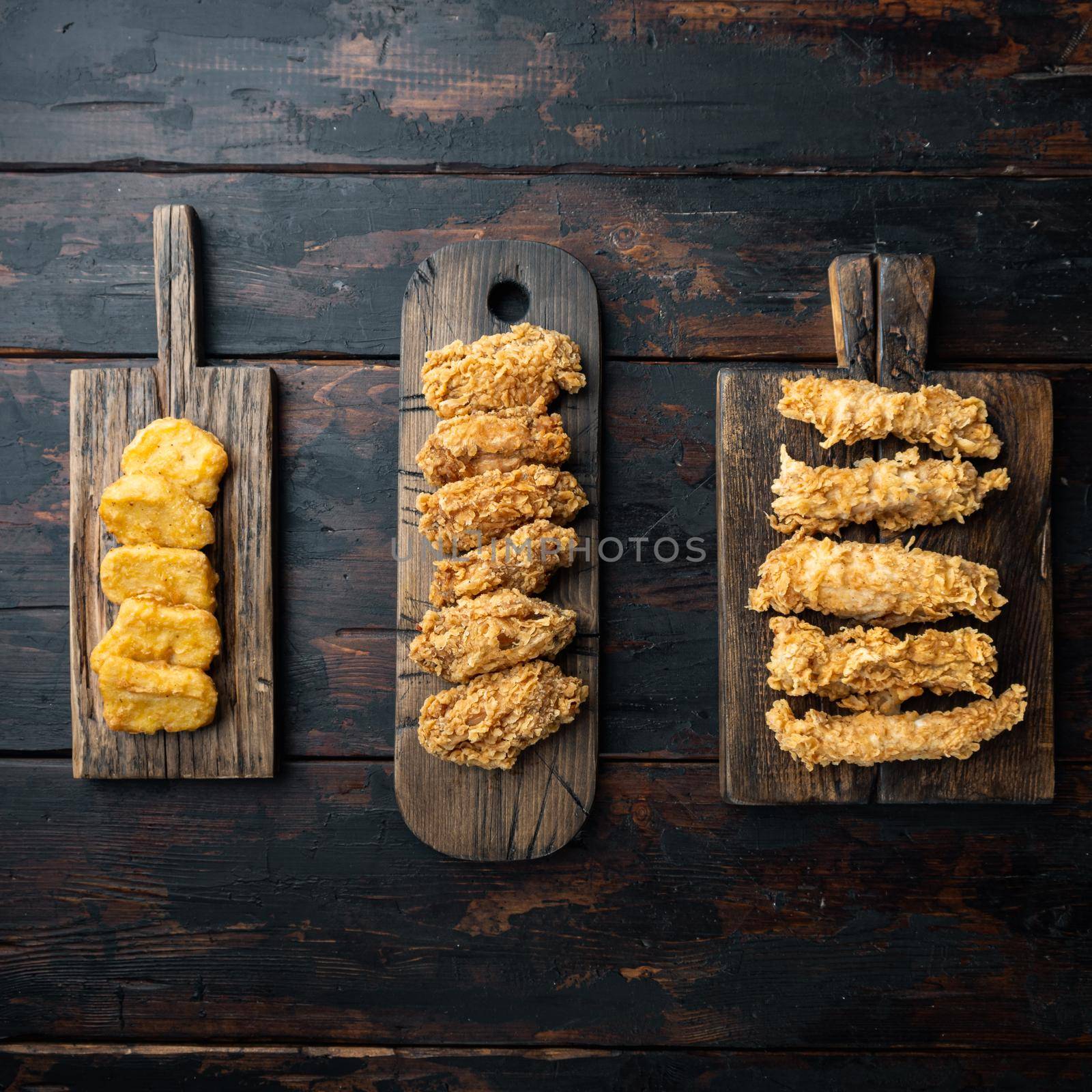 Crispy fried chicken parts on old dark wooden table, top view.