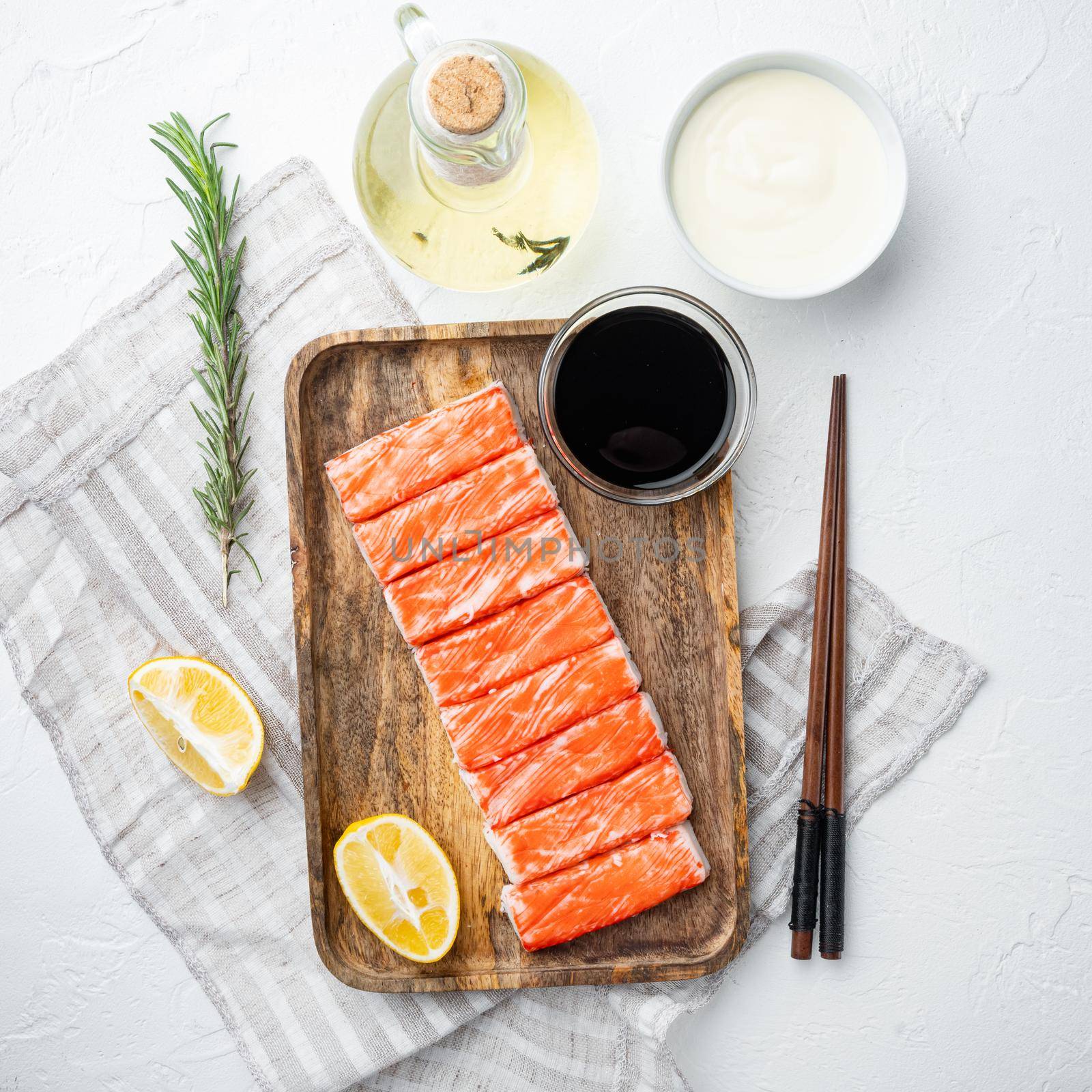 Fresh Crab meat stick surimi with blue swimming crab, on wooden tray, on white background, top view flat lay by Ilianesolenyi