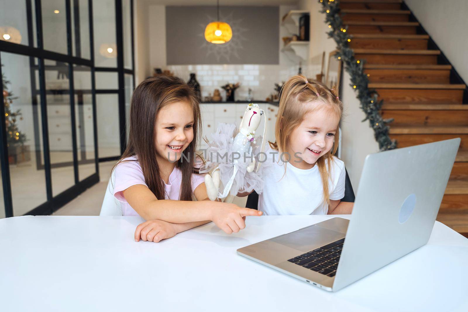 Two little girls playing together at the laptop while sitting