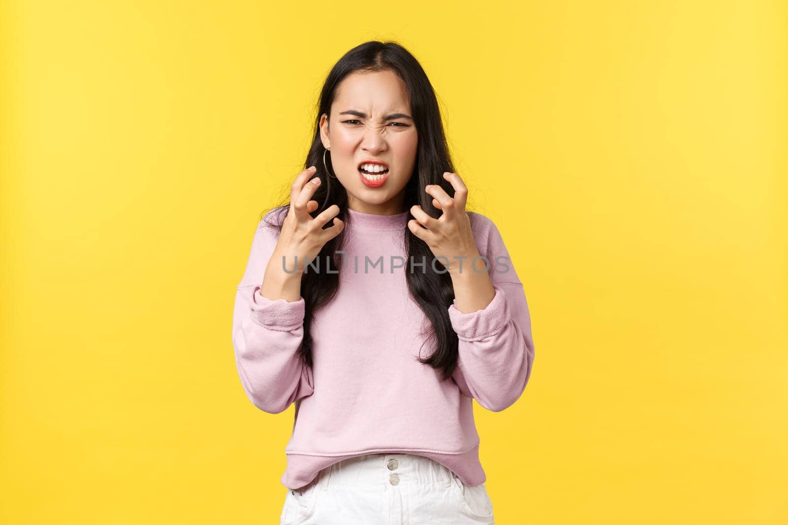 Lifestyle, emotions and advertisement concept. Outraged and pissed-off asian girl looking mad and aggressive clench fists, want kill someone, grimacing angry, standing yellow background by Benzoix