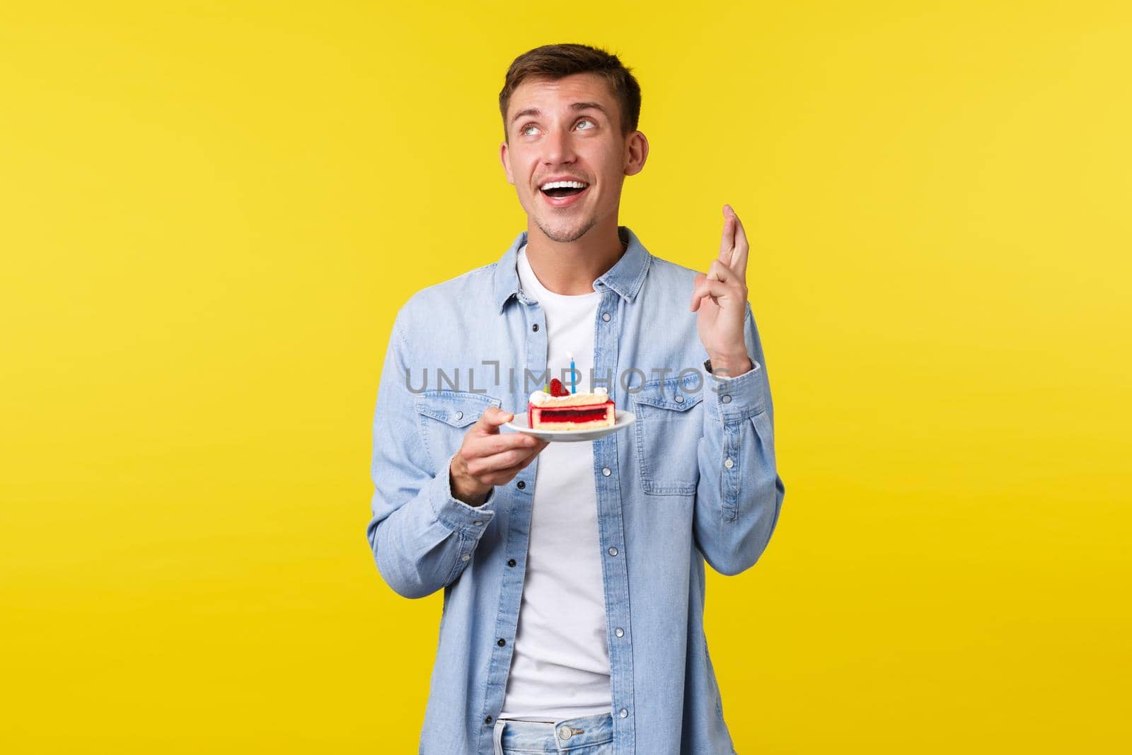 Celebration, holidays and people emotions concept. Dreamy happy birthday guy celebrating b-day, holding cake and looking away while making wish, cross fingers for good luck by Benzoix