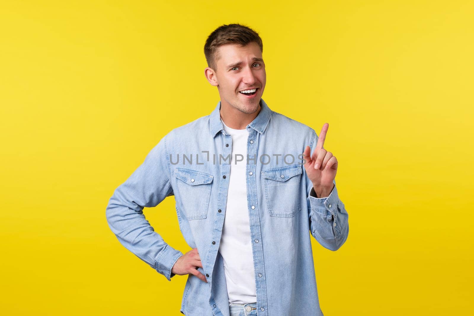 Cheerful smiling blond man shaking finger, tell not so fast, scolding someone or asking hold on, wait sec, standing yellow background upbeat, showing advertisement on top.