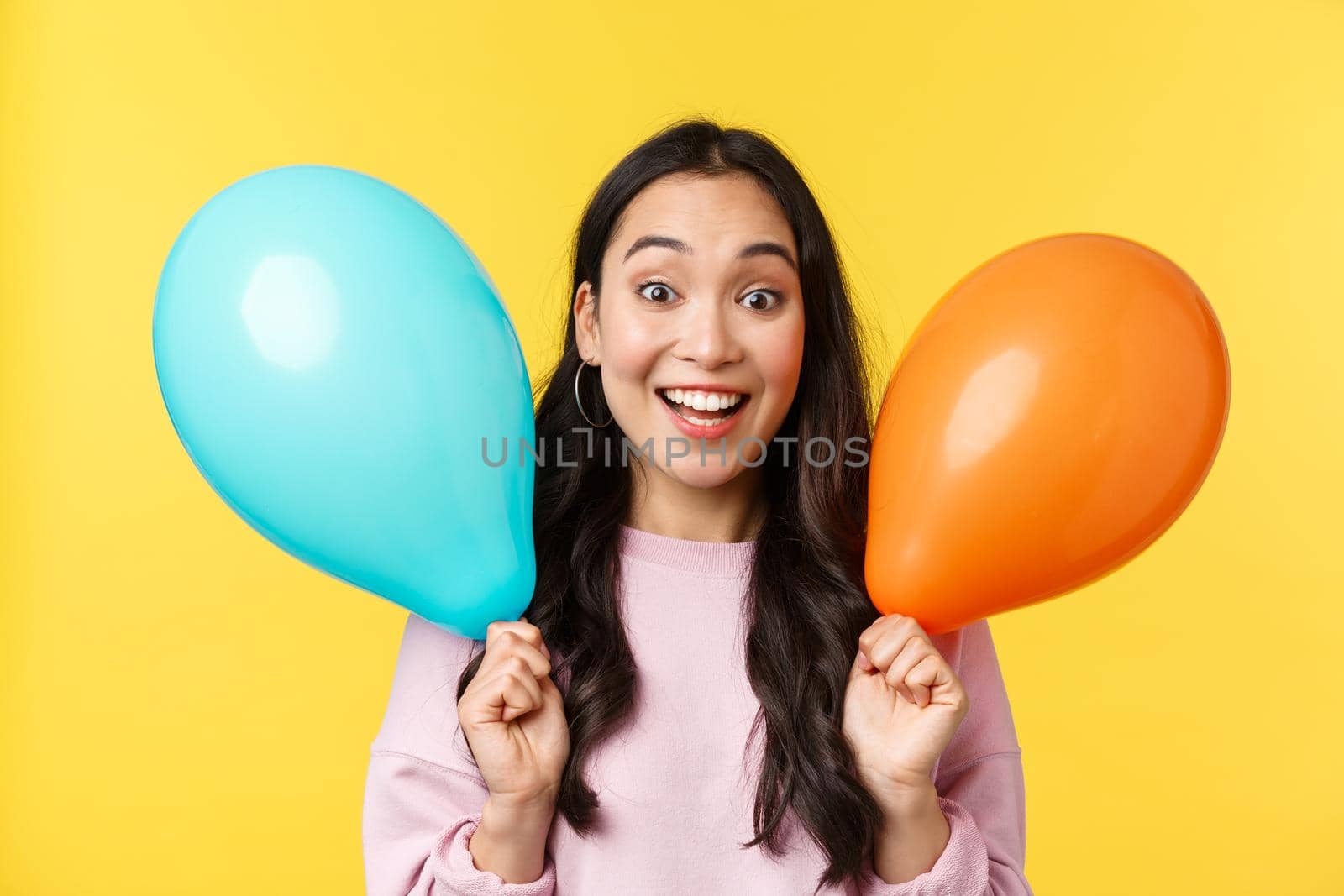People emotions, lifestyle leisure and beauty concept. Cheerful happy asian girl congratulate with big holiday, holding two balloons and smiling broadly, enjoy party over yellow background by Benzoix