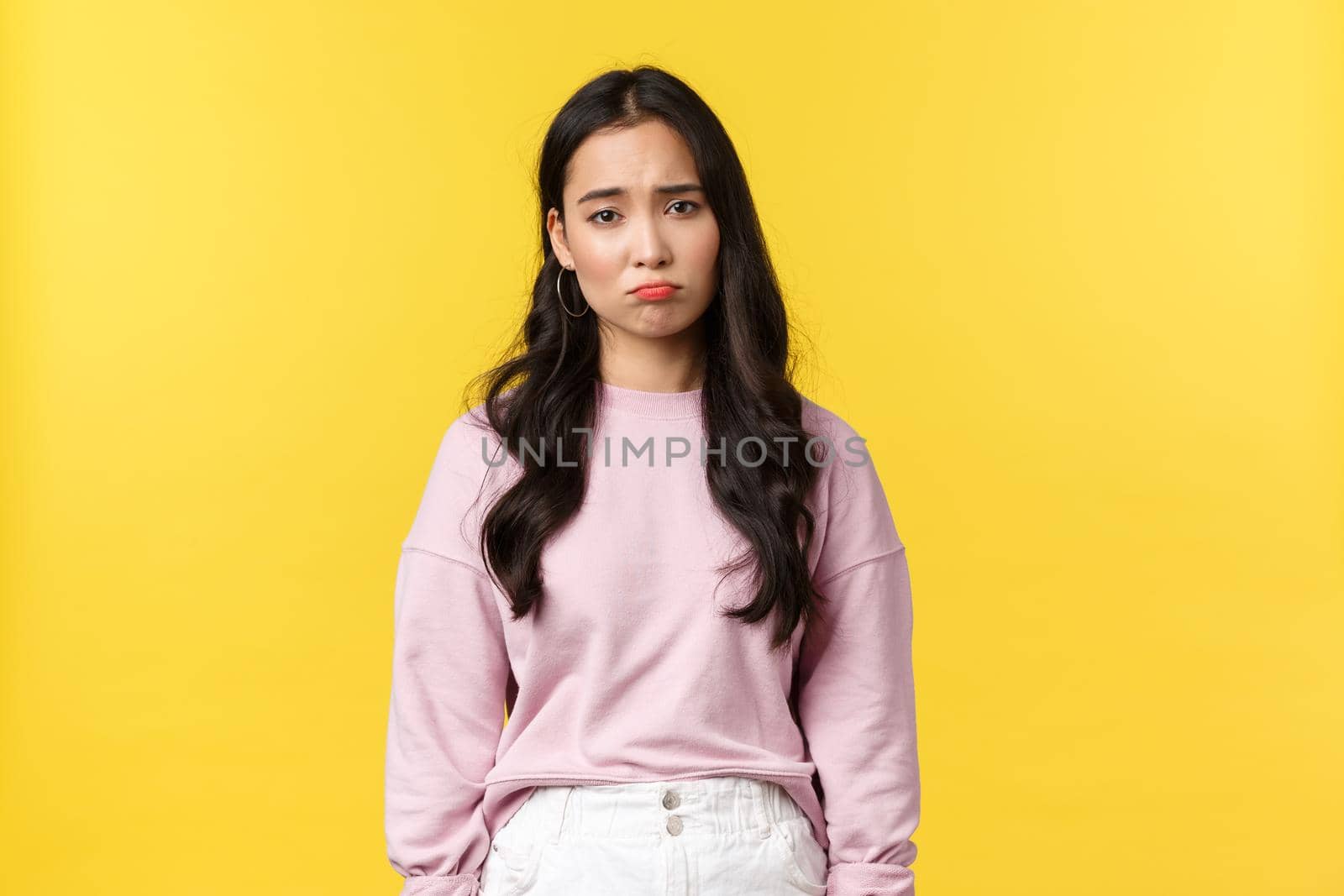 People emotions, lifestyle and fashion concept. Depressed and sad, gloomy korean girl pouting, looking down in dumps, feeling upset and displeased, standing yellow background by Benzoix