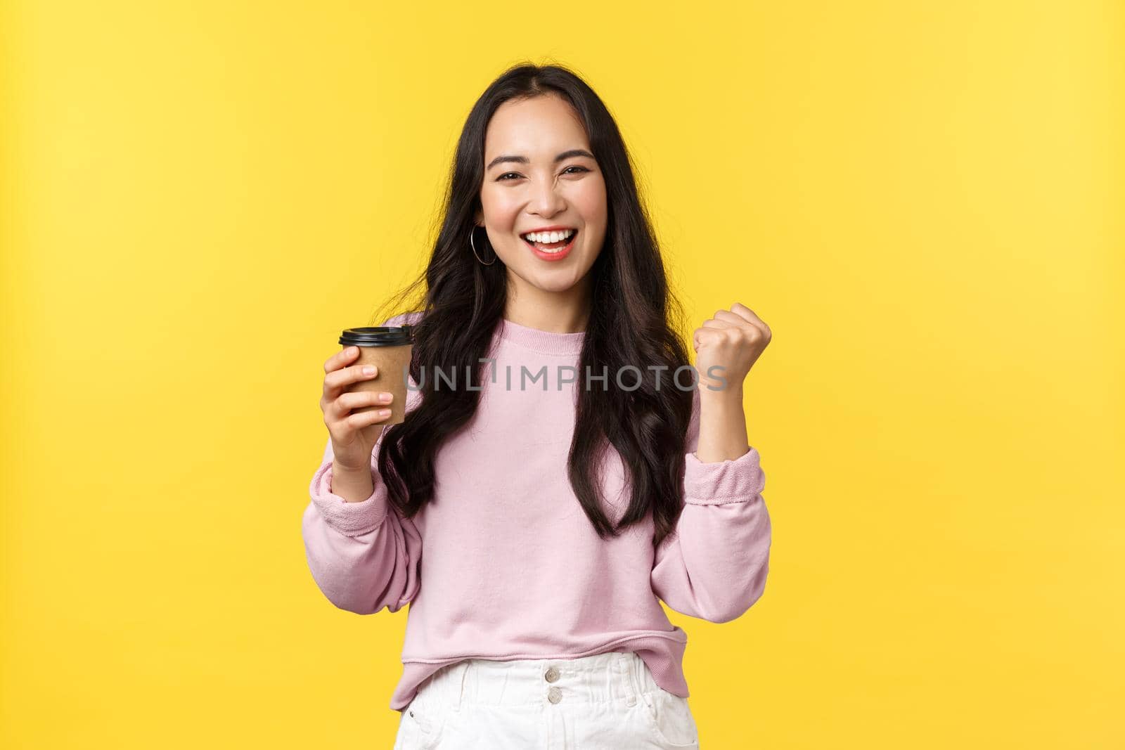 People emotions, lifestyle leisure and beauty concept. Enthusiastic and energized smiling asian woman drinking cup of tasty coffee from best cafe takeaway, fist pump happy, got pumped up.