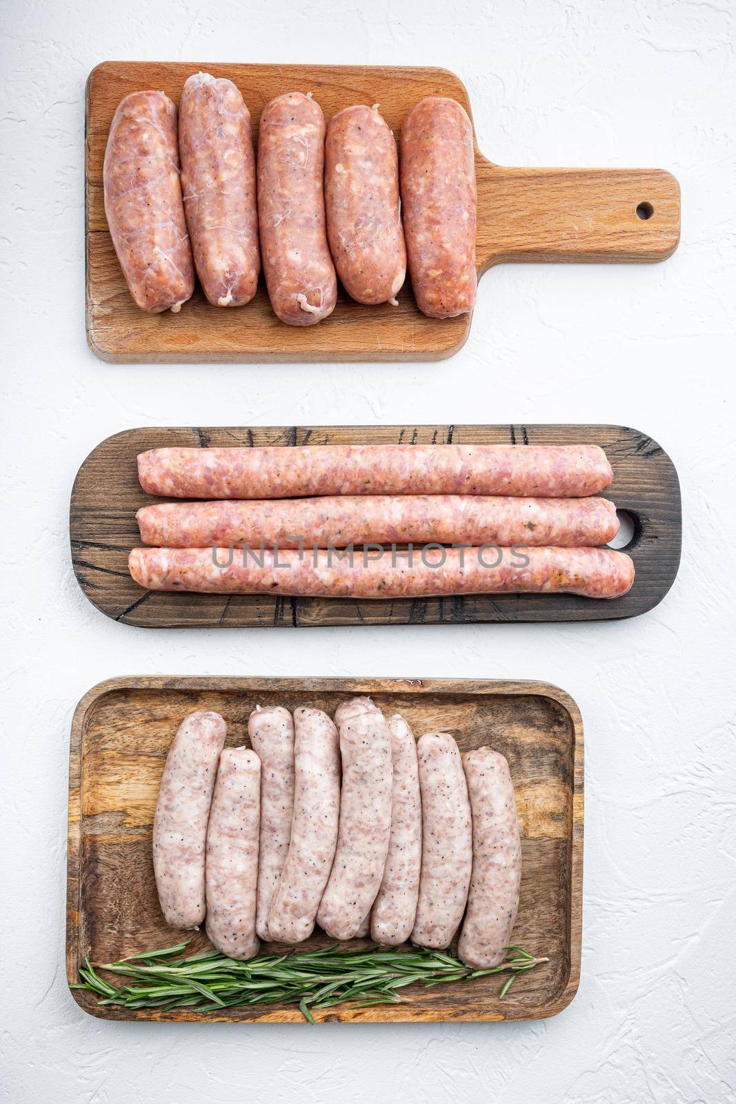 Fresh raw pork, beef and chicken sausages, top view, on white background.