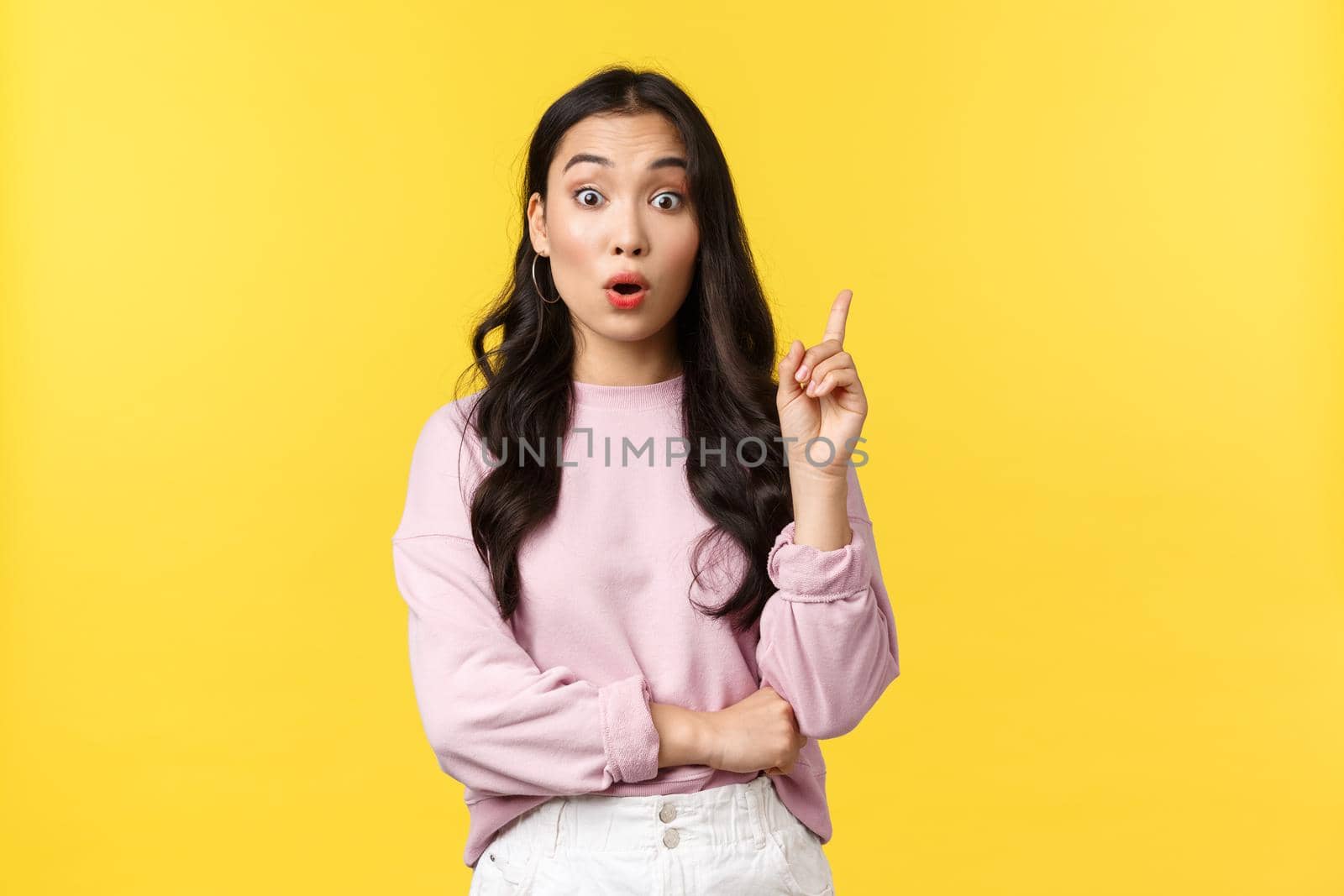 People emotions, lifestyle and fashion concept. Thoughtful excited stylish asian woman have idea, raising index finger and say suggestion, have plan, think-up solution, standing yellow background.