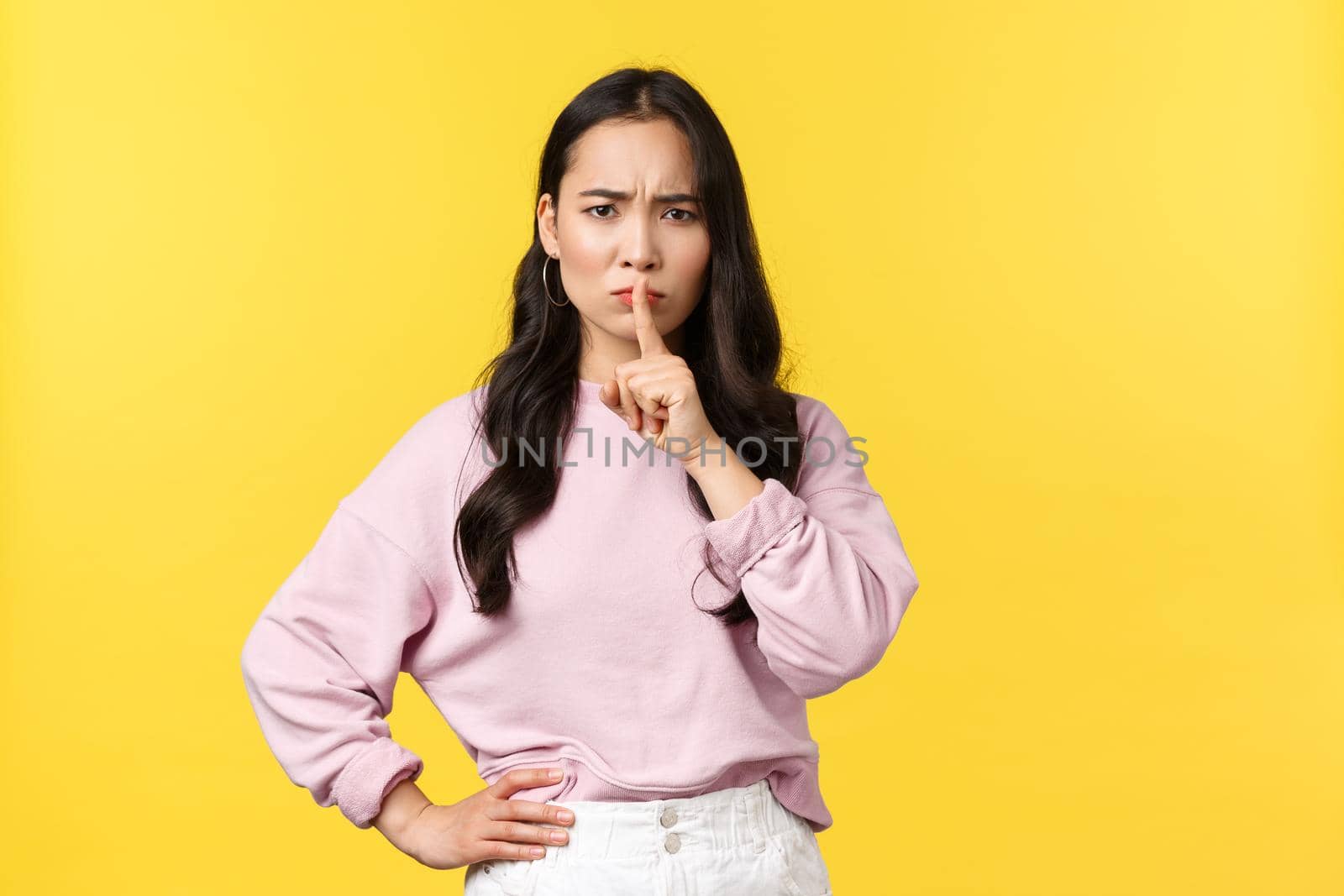 People emotions, lifestyle and fashion concept. Angry displeased young asian woman tell be quiet, shushing with disappointed face, hush with finger pressed to lips dissatisfied, yellow background by Benzoix