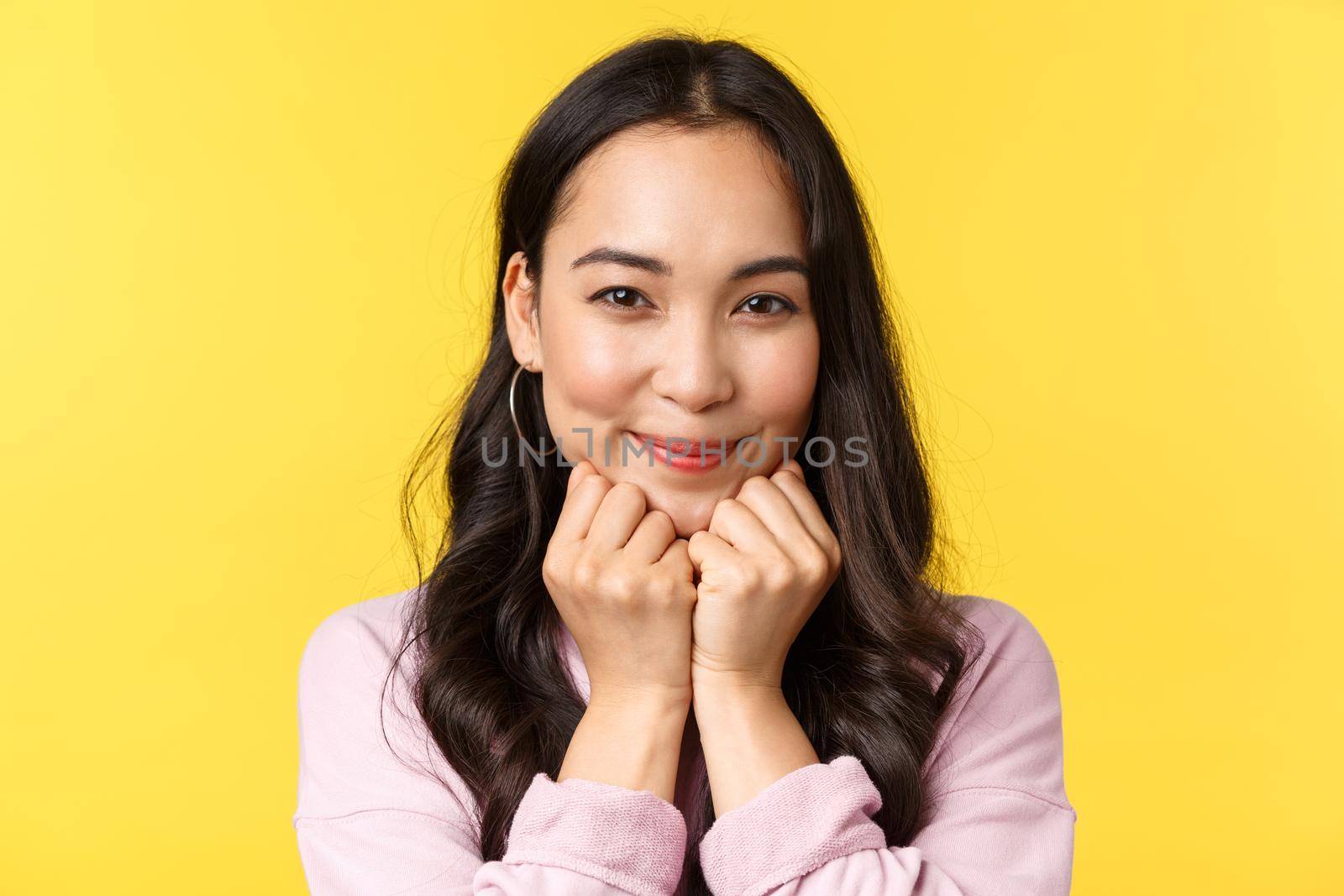 People emotions, lifestyle leisure and beauty concept. Lovely asian woman smiling at camera and looking sympathy, affection, feeling joy and love, advertise shop, stand yellow background.