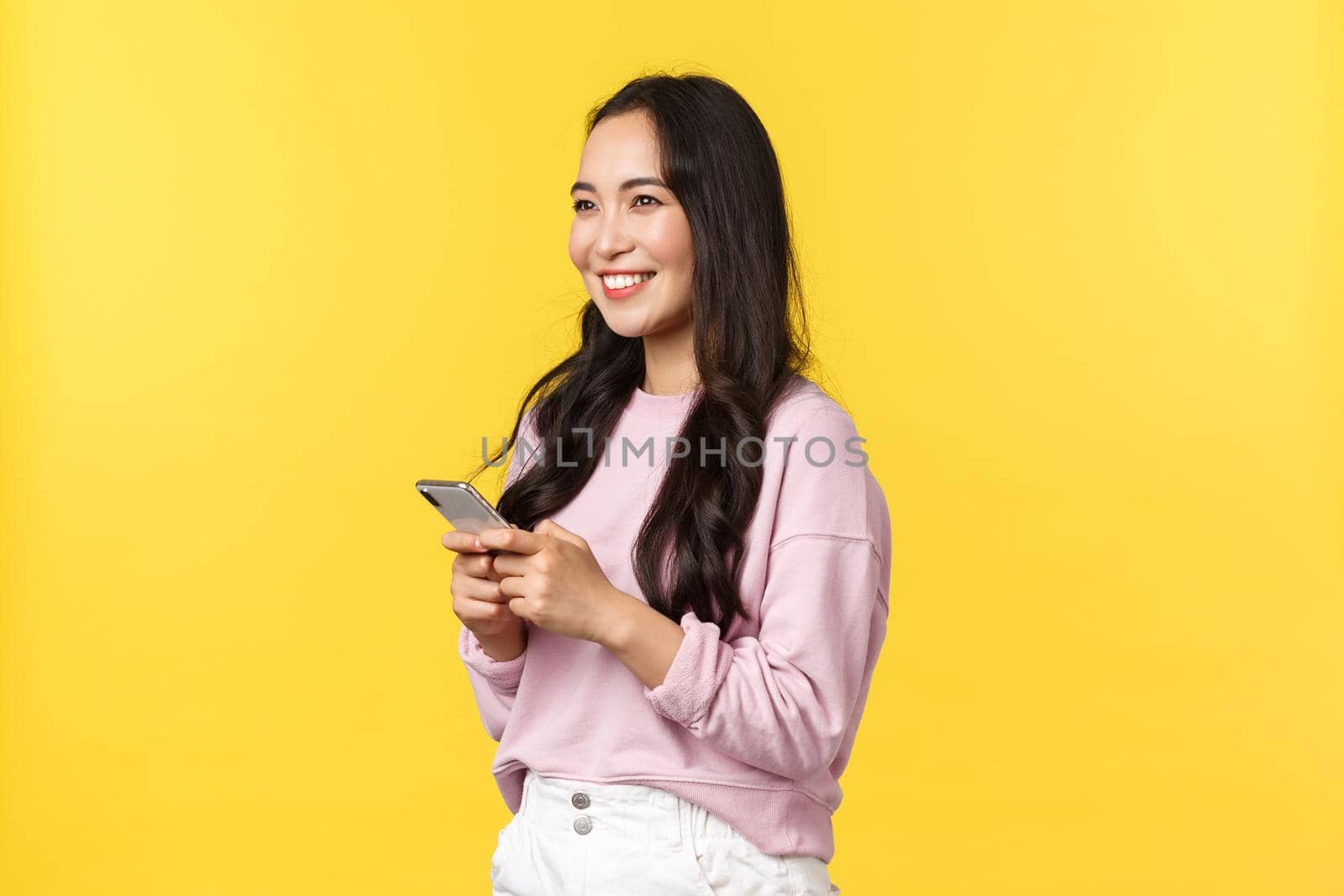 People emotions, lifestyle leisure and beauty concept. Profile shot of smiling japanese girl using smartphone and looking left pleased. Dreamy asian woman using carsharing app to call taxi by Benzoix