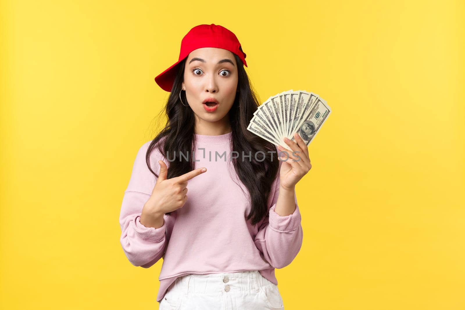 People emotions, lifestyle leisure and beauty concept. Surprised and amazed, overwhelmed cute asian girl with lots of cash, pointing at money and drop jaw, win lottery, got bonus for good work.