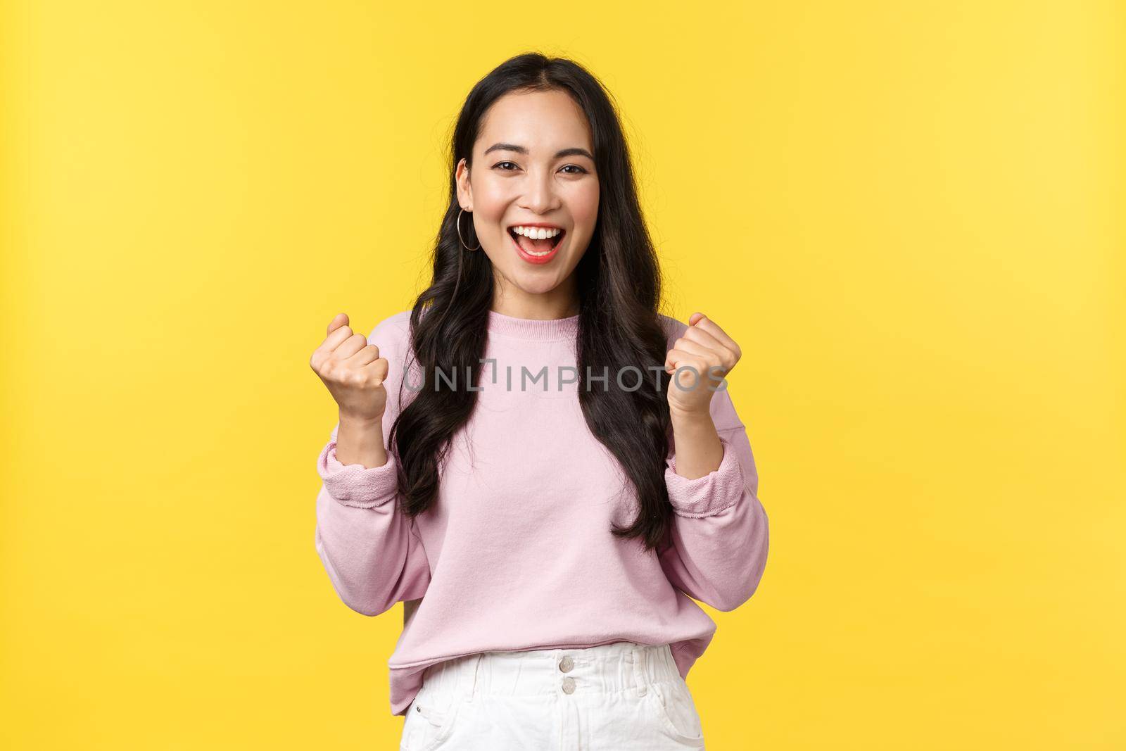 Lifestyle, emotions and advertisement concept. Cheerful and excited cute asian girl winning lottery, feel luck and upbeat, triumphing over achievement, say yes and fist pump rejoicing.