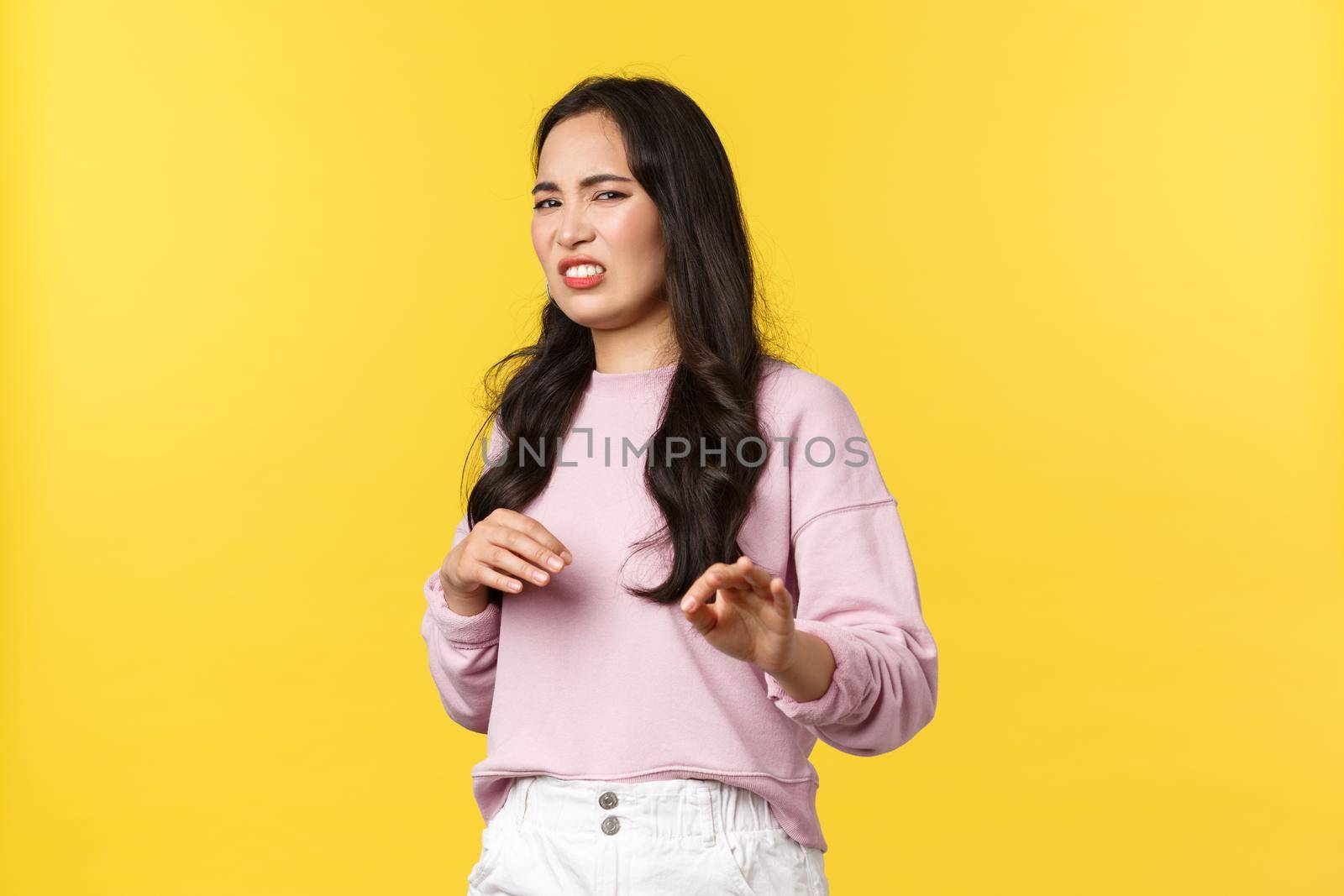 People emotions, lifestyle and fashion concept. Gross stay away from me. Disgusted picky and arrogant asian woman gesturing and step back with aversion, rejecting offer, refusing, yellow background.