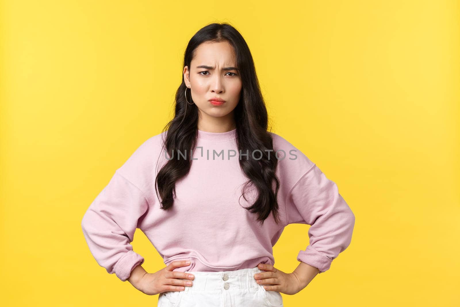 People emotions, lifestyle and fashion concept. Disappointed and mad asian girlfriend in stylish outfit, frowning hold hands on waist, scolding someone, having argument, yellow background by Benzoix