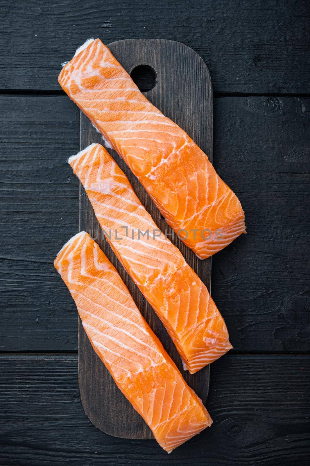 Raw salmon fillet, on black wooden table, top view