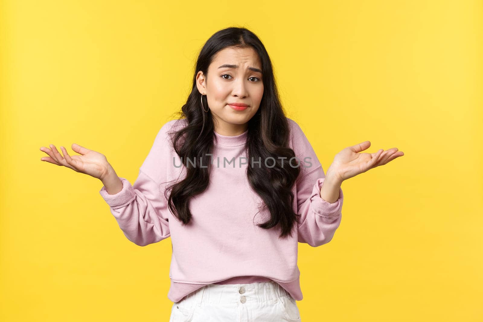 People emotions, lifestyle and fashion concept. Indecisive and clueless cute asian woman shrugging, smirk perplexed and shaking head, dont know, cant understand anything, yellow background by Benzoix
