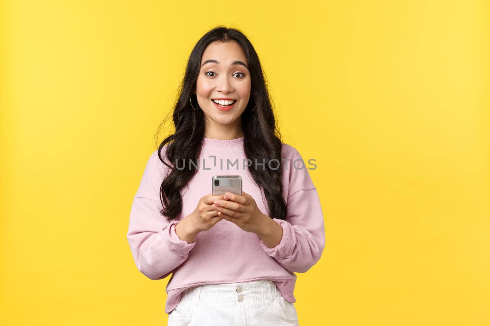 People emotions, lifestyle leisure and beauty concept. Happy and surprised pretty korean girl in stylish outfit, looking amazed with broad smile camera after reading great news in mobile app by Benzoix