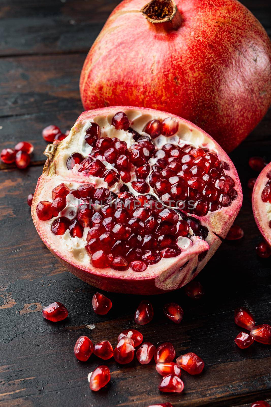 Ripe pomegranate with juicy seeds, on old wooden table