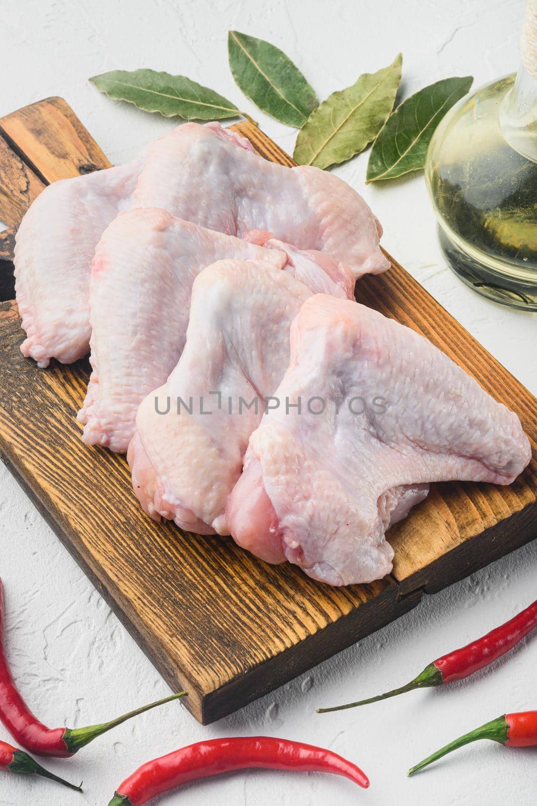 Fresh raw chicken wings with spices and herbs, on wooden cutting board, on white background by Ilianesolenyi