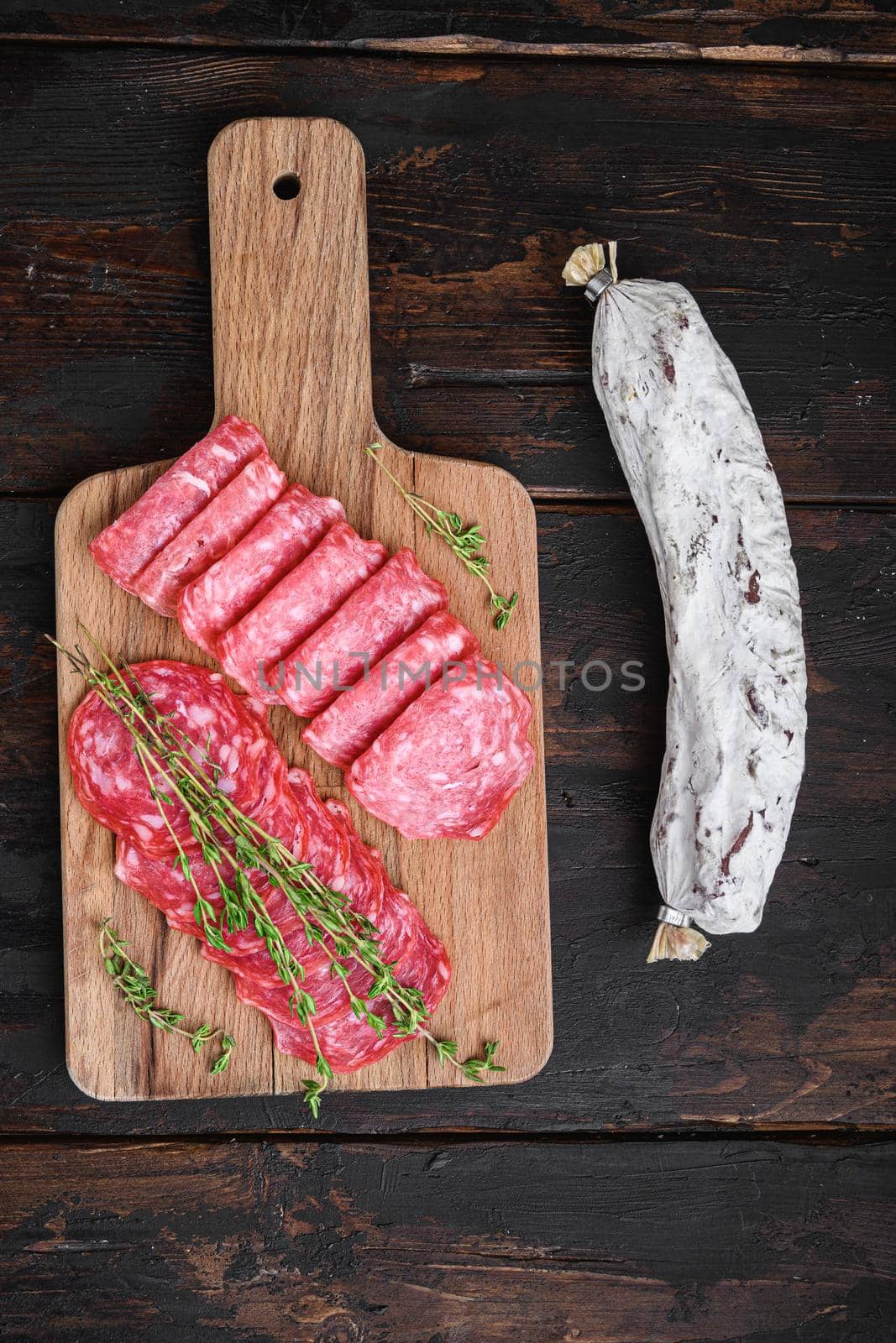 Salchichon sausages cut in slices on dark wooden background, topview.