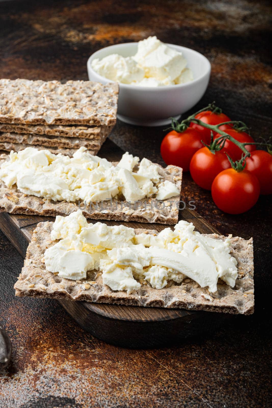 Crisp bread with cream cheese set, on old dark rustic table background