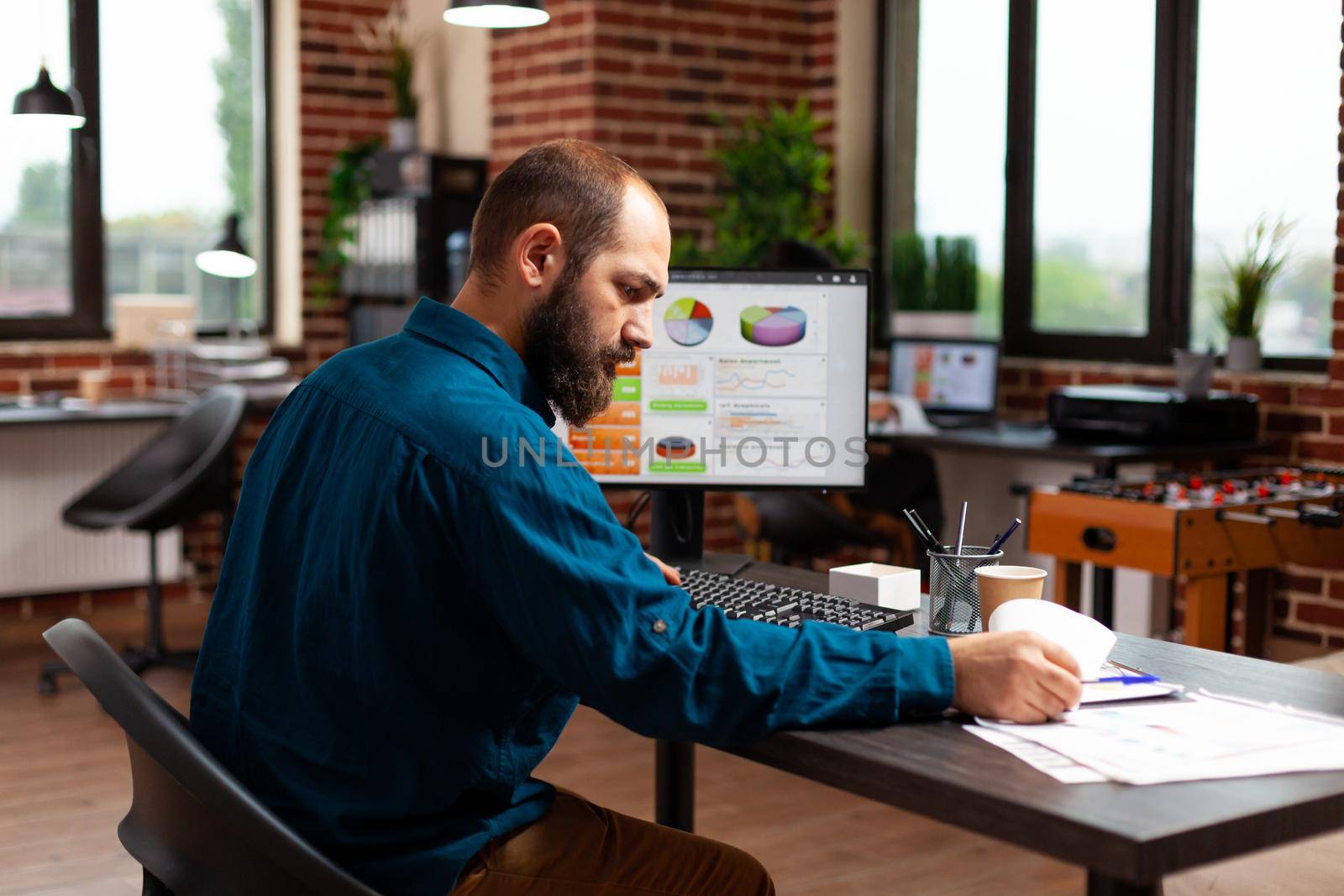 Entrepreneur man sitting at desk table analyzing business documents working at marketing presentation by DCStudio