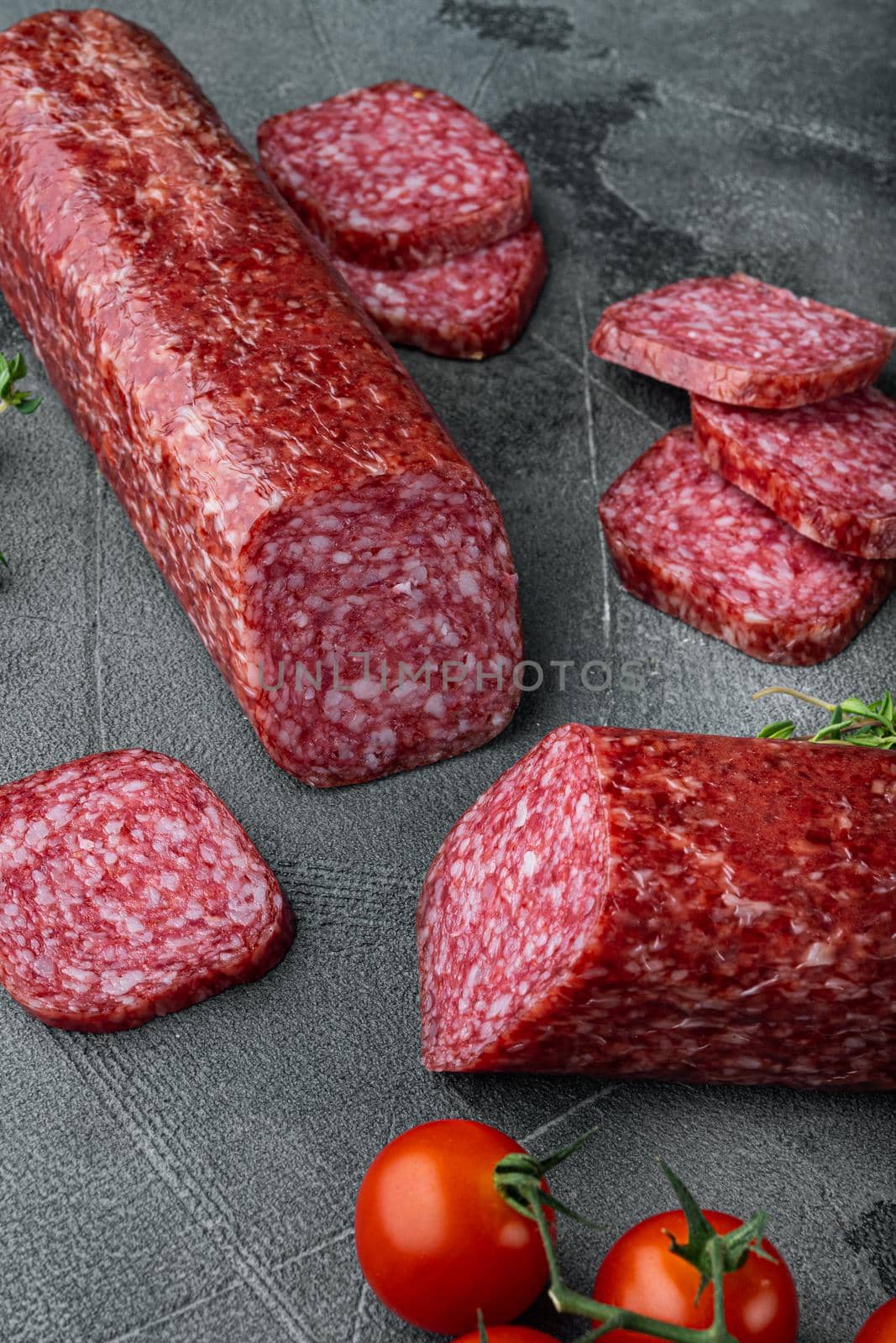 Dry salami sausage with fresh rosemary and spices, on gray stone table background by Ilianesolenyi