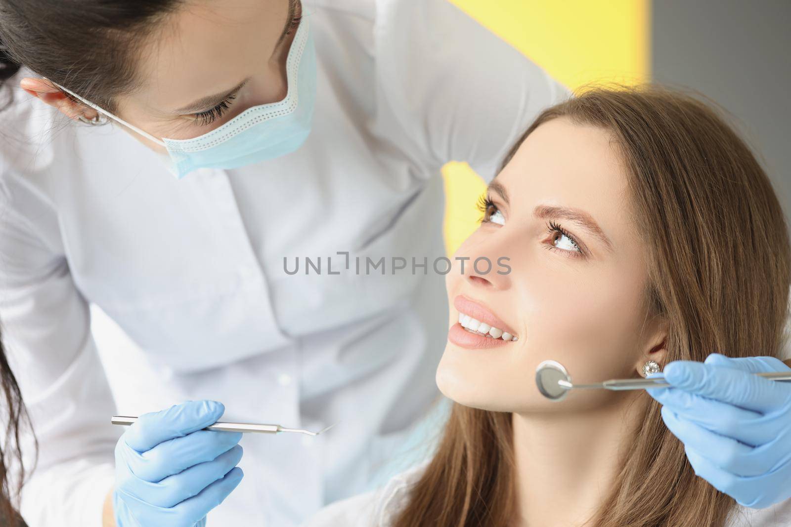 Portrait of female in dentist chair, appointment in dental clinic. Dentist woman ask to open mouth for examination. Medicine, dental, stomatology concept