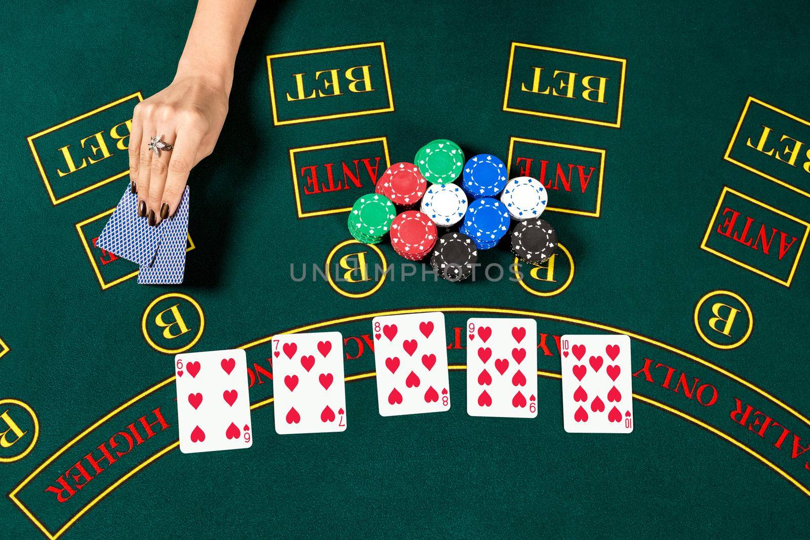 Poker play. Chips in a player's hand. top view. female hand lifts the cards to see