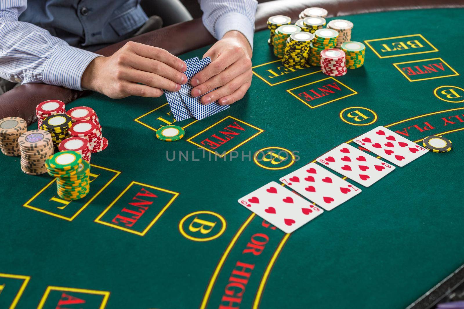 Close up of poker player with playing cards and chips at green casino table