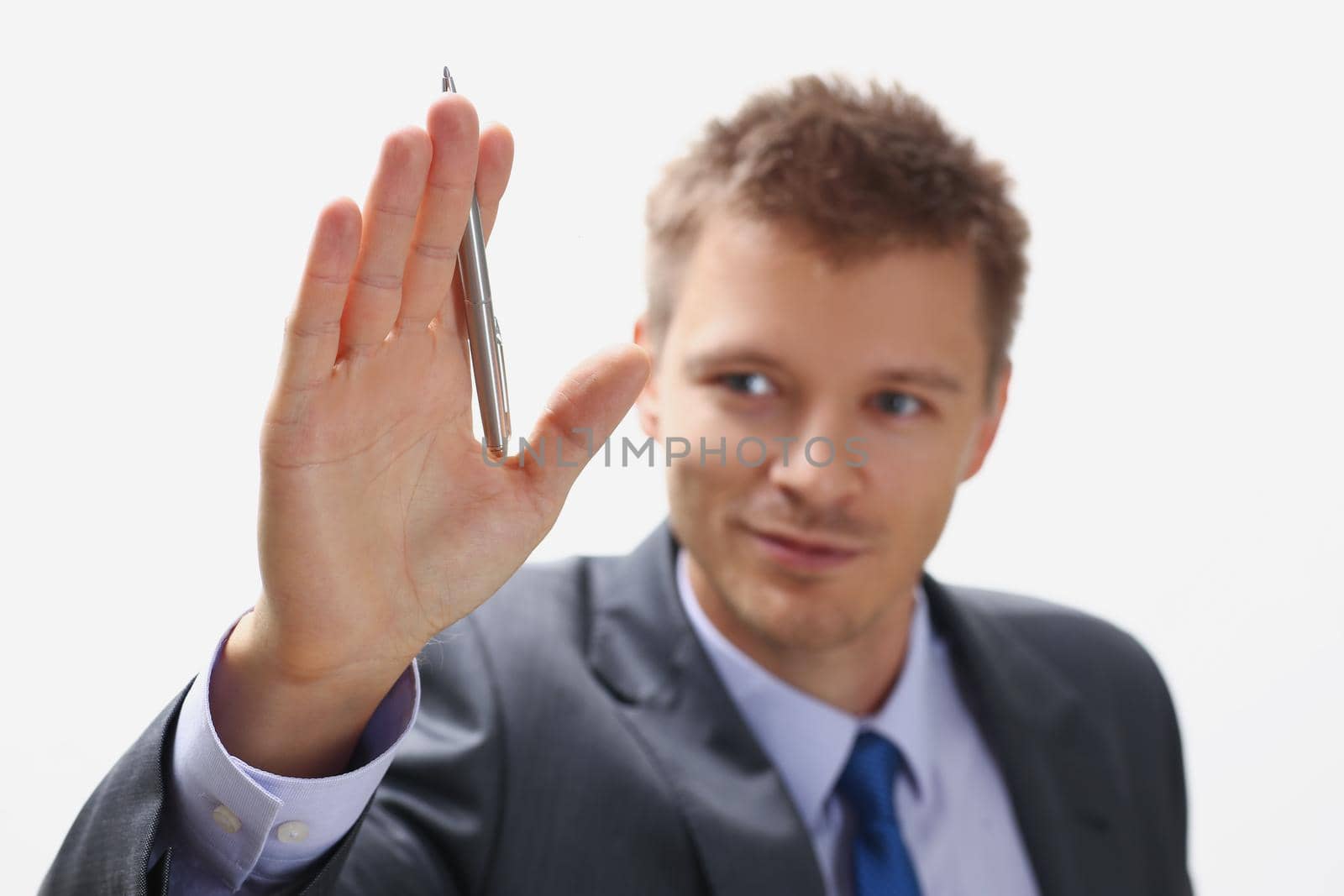 Portrait of handsome businessman wave hello holding silver pen on hand. Successful man in presentable suit, productive manager at work. Business concept