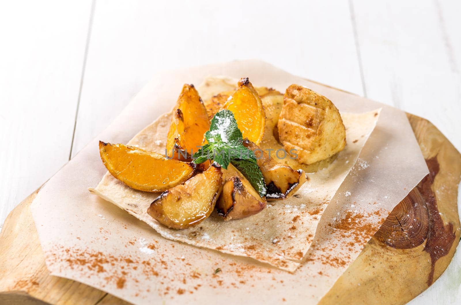 Fruits grilled with mint close up on a wooden board on white table. Takeaway composition