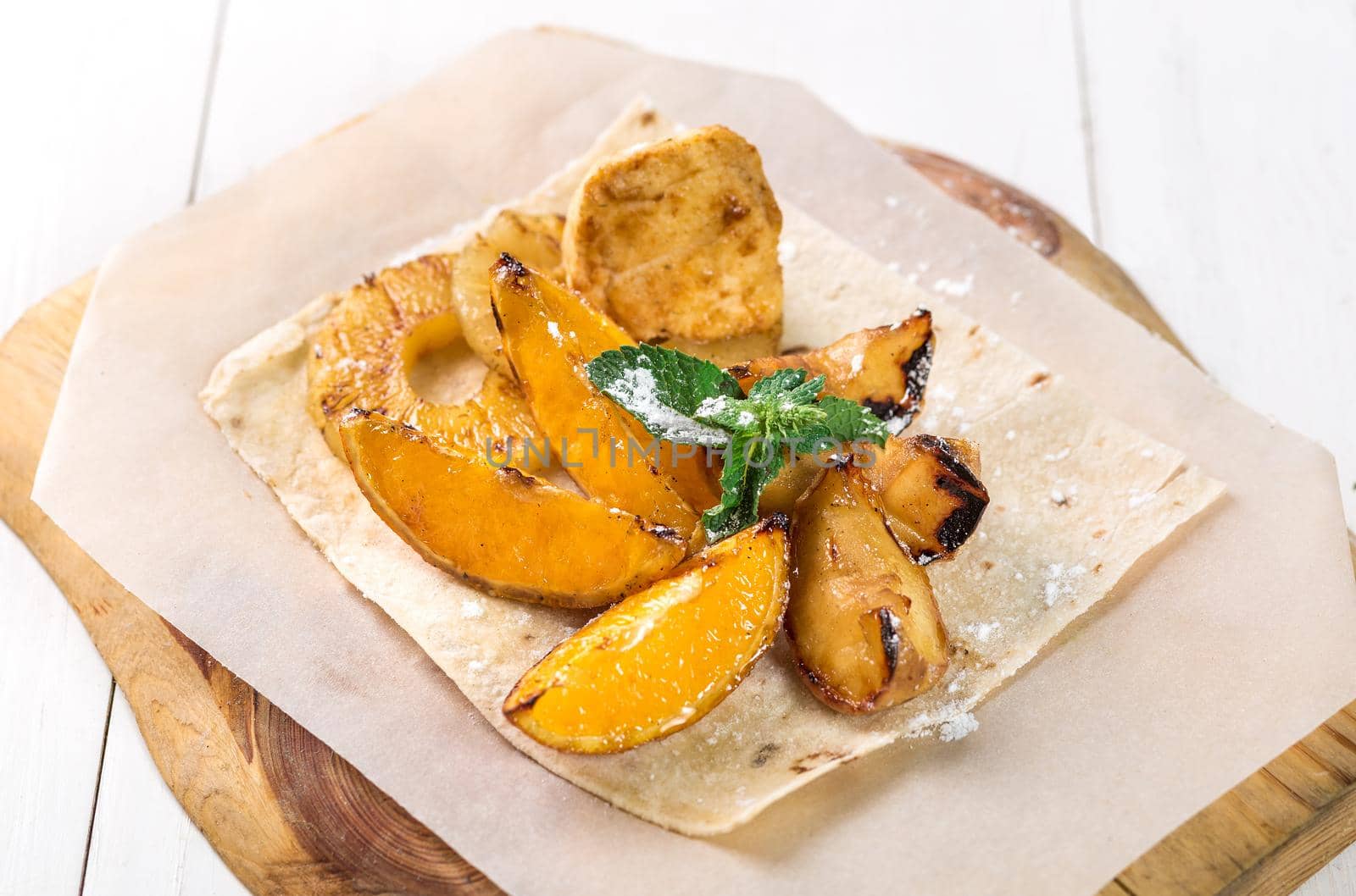 Fruits grilled with mint close up on a wooden board on white table. Takeaway composition