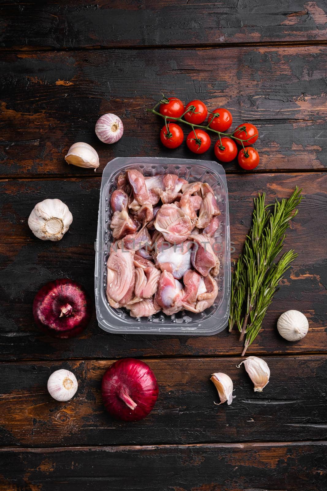 Bird chicken giblets gizzards stomachs Raw uncooked plastic pack, on old dark wooden table background, top view flat lay by Ilianesolenyi