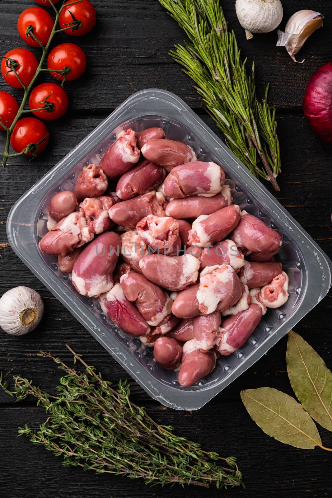 Chicken hearts in plastic tray, on black wooden table background, top view flat lay by Ilianesolenyi